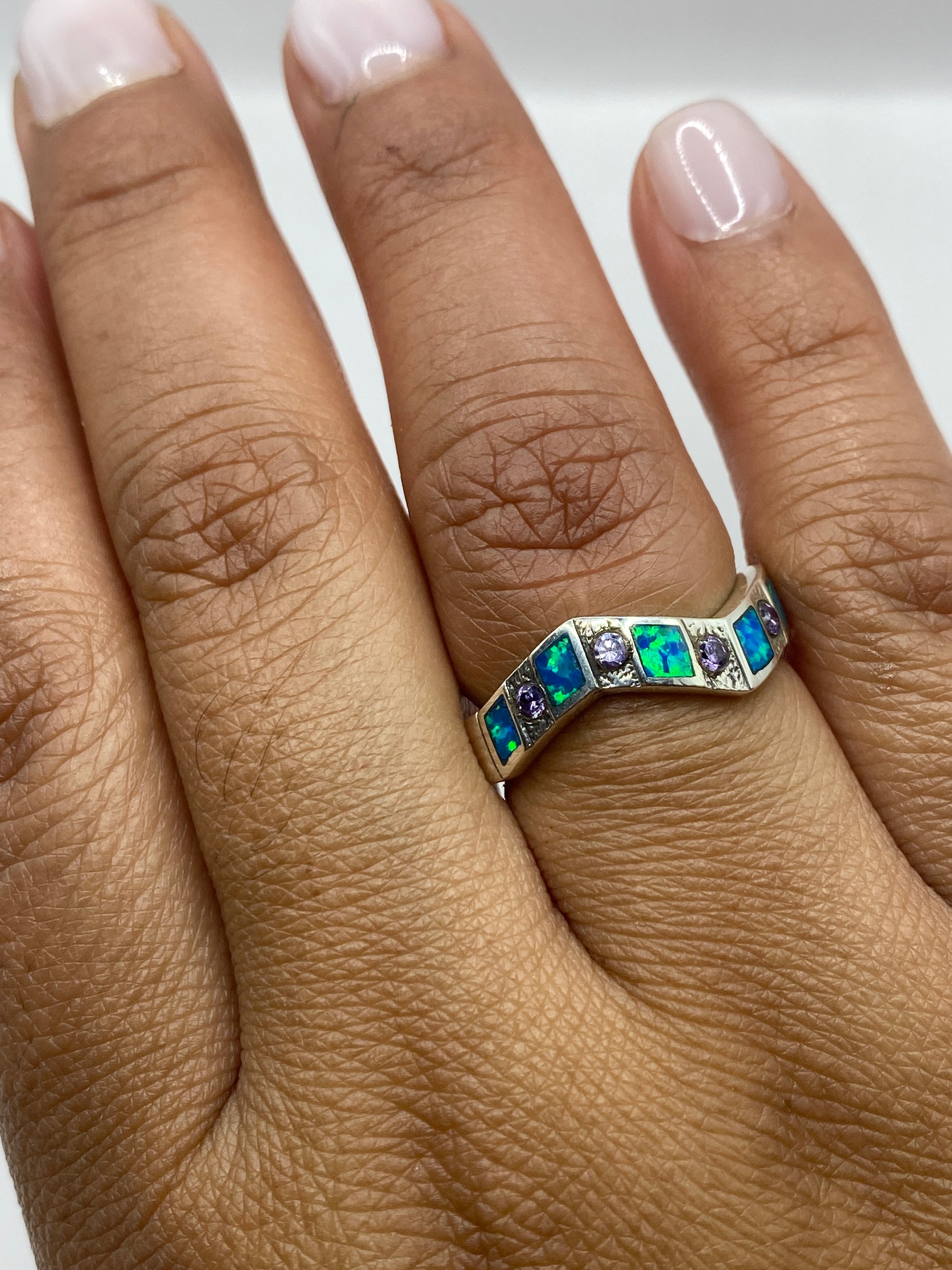 Anillo geométrico en mano femenina, luciendo la alternancia azul-verde del ópalo