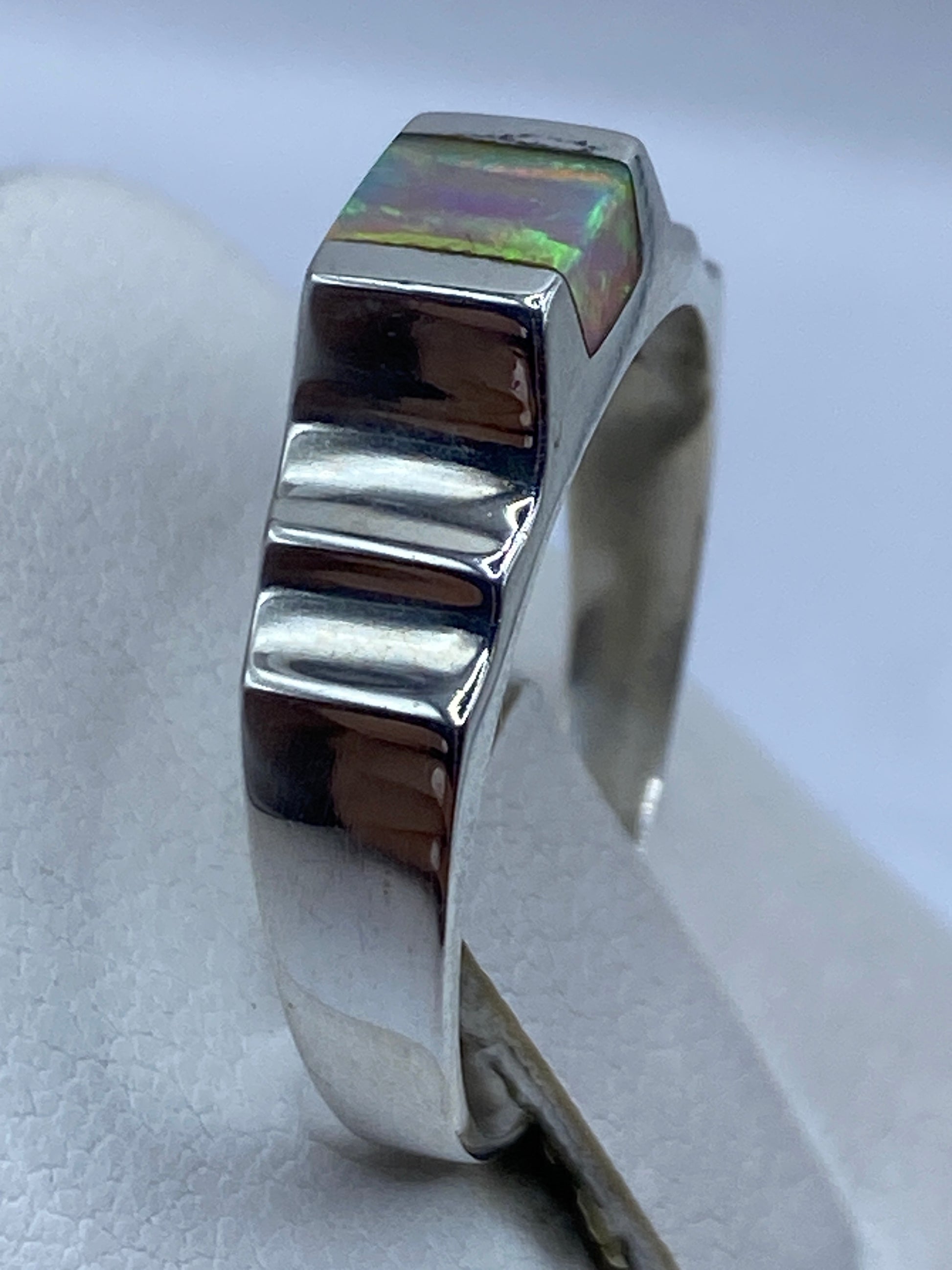 Anillo ópalo de fuego en la mano mostrando el juego de colores bajo la luz natural