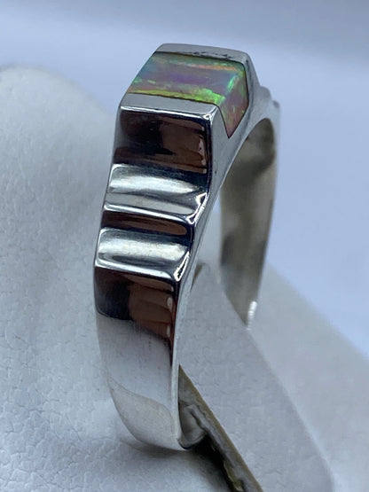 Anillo ópalo de fuego en la mano mostrando el juego de colores bajo la luz natural