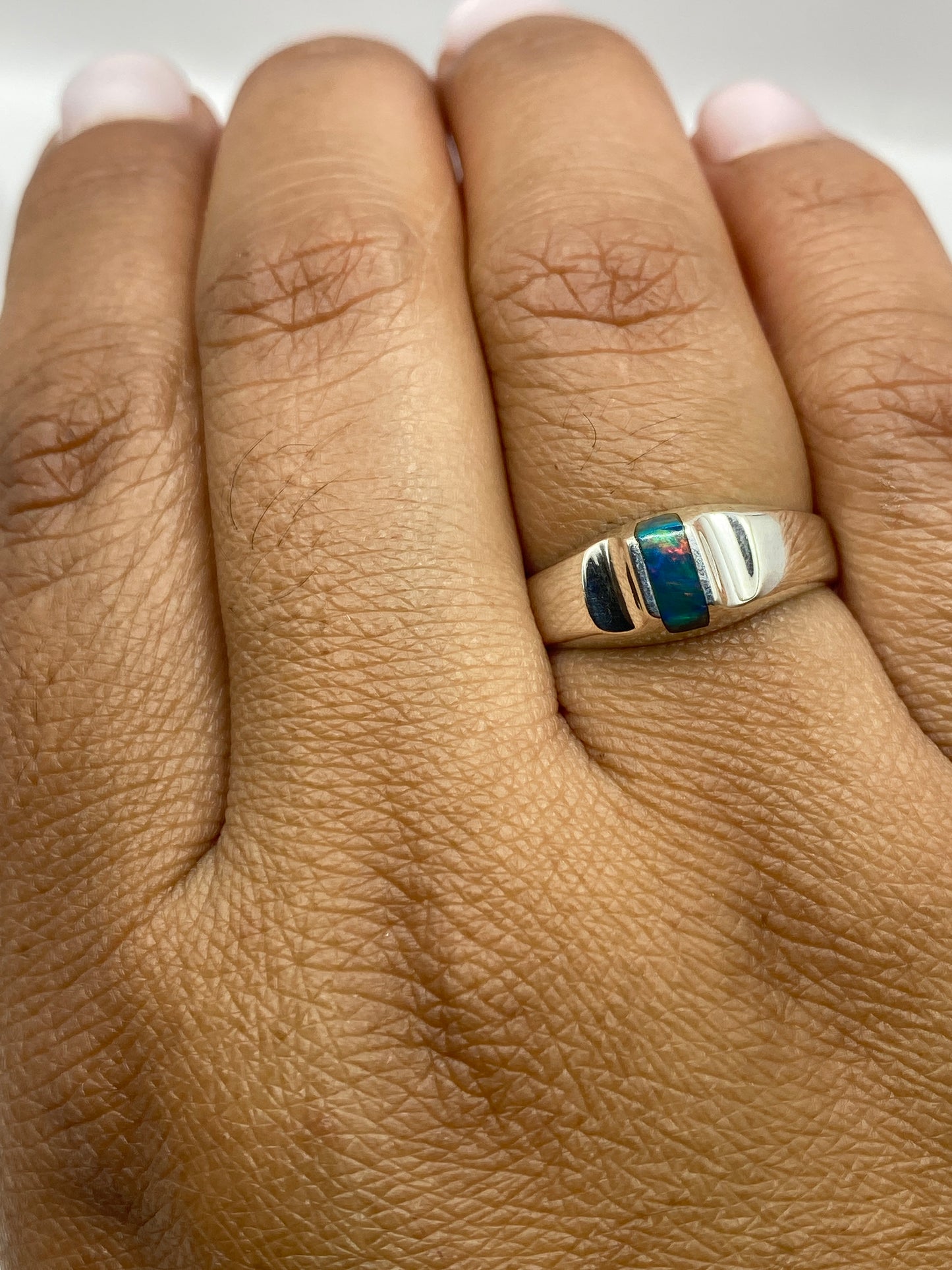 Anillo solitario de ópalo sobre fondo blanco mostrando sello 925 en la banda