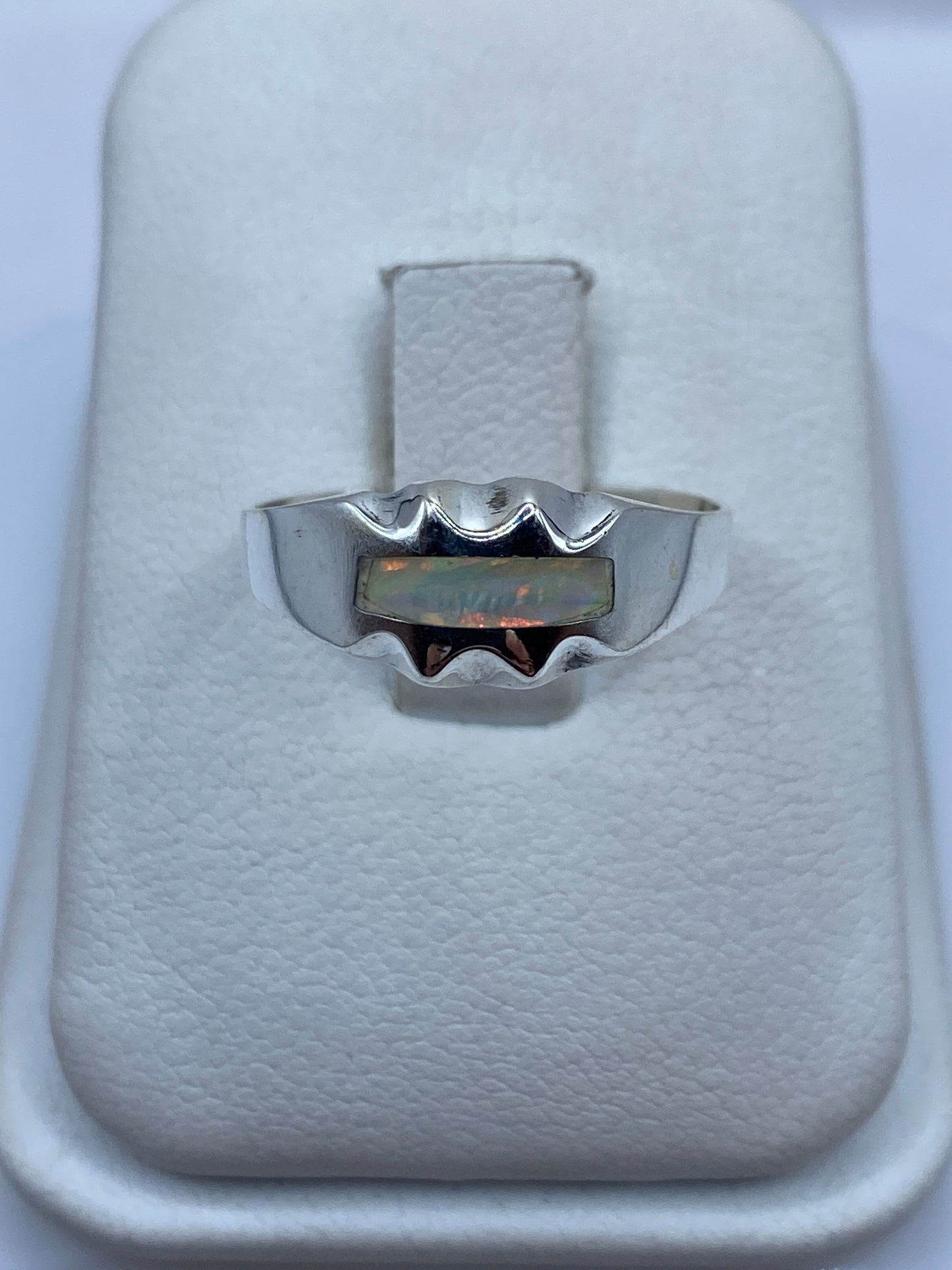 Anillo de plata con ópalo de fuego mostrando azul, verde y naranja en luz natural