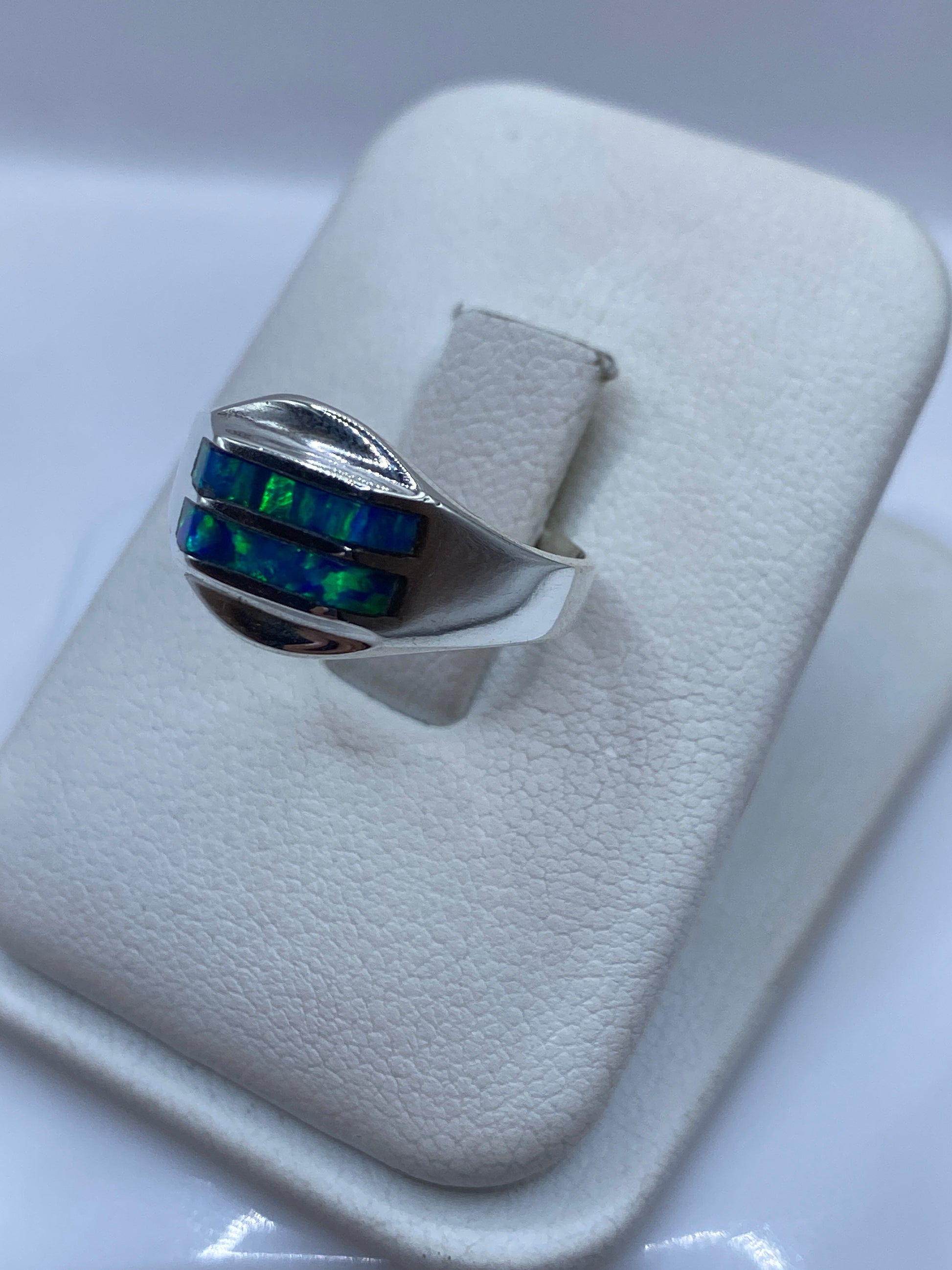 Vista frontal del anillo mostrando el juego de colores azul y verde del ópalo