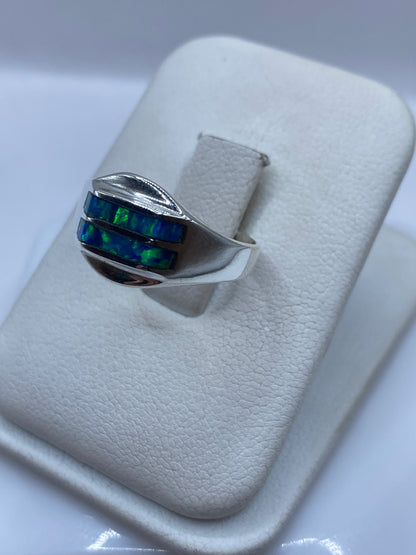 Vista frontal del anillo mostrando el juego de colores azul y verde del ópalo