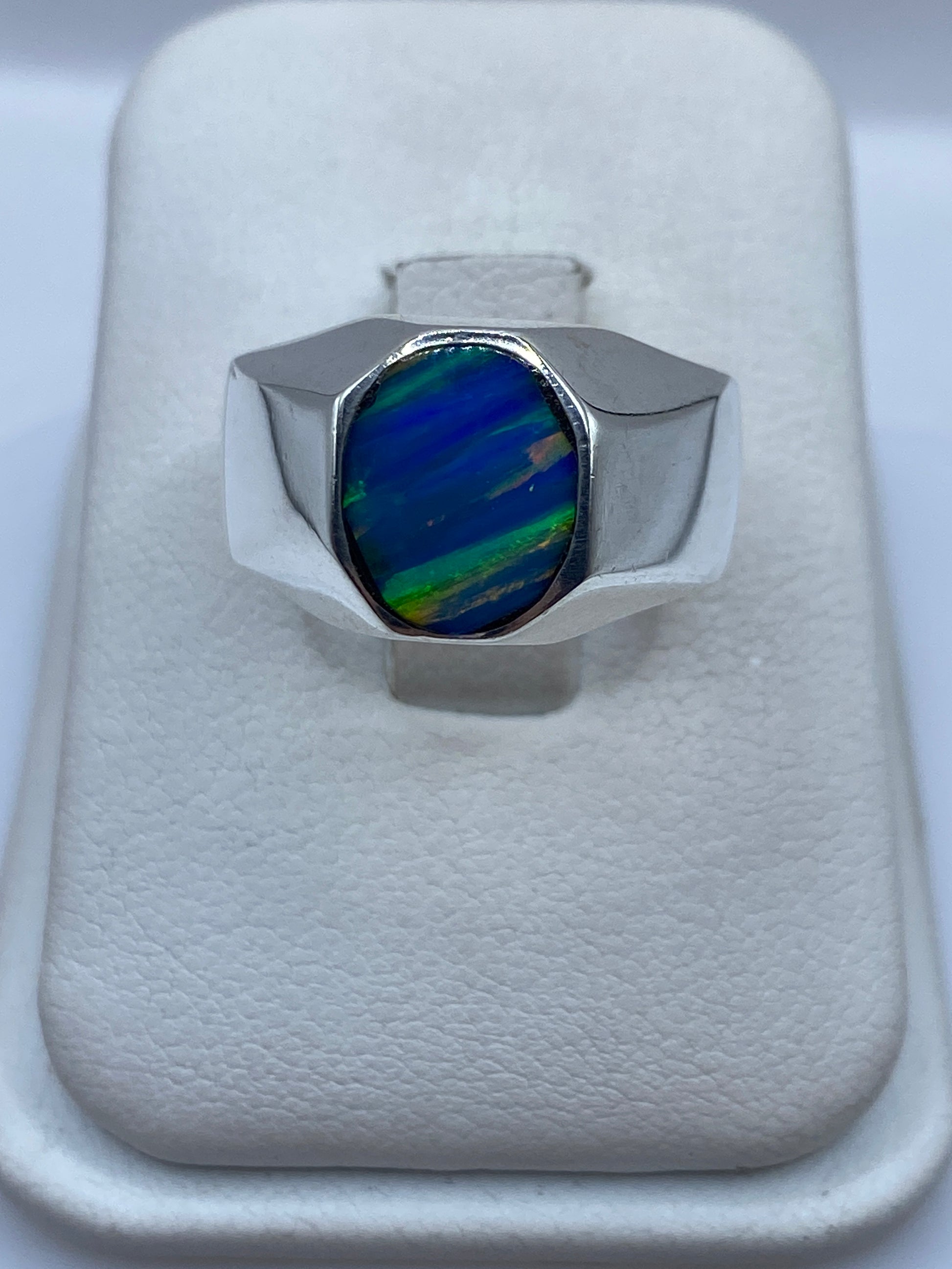 Anillo de plata sello con ópalo de fuego azul, vista frontal sobre presentador blanco