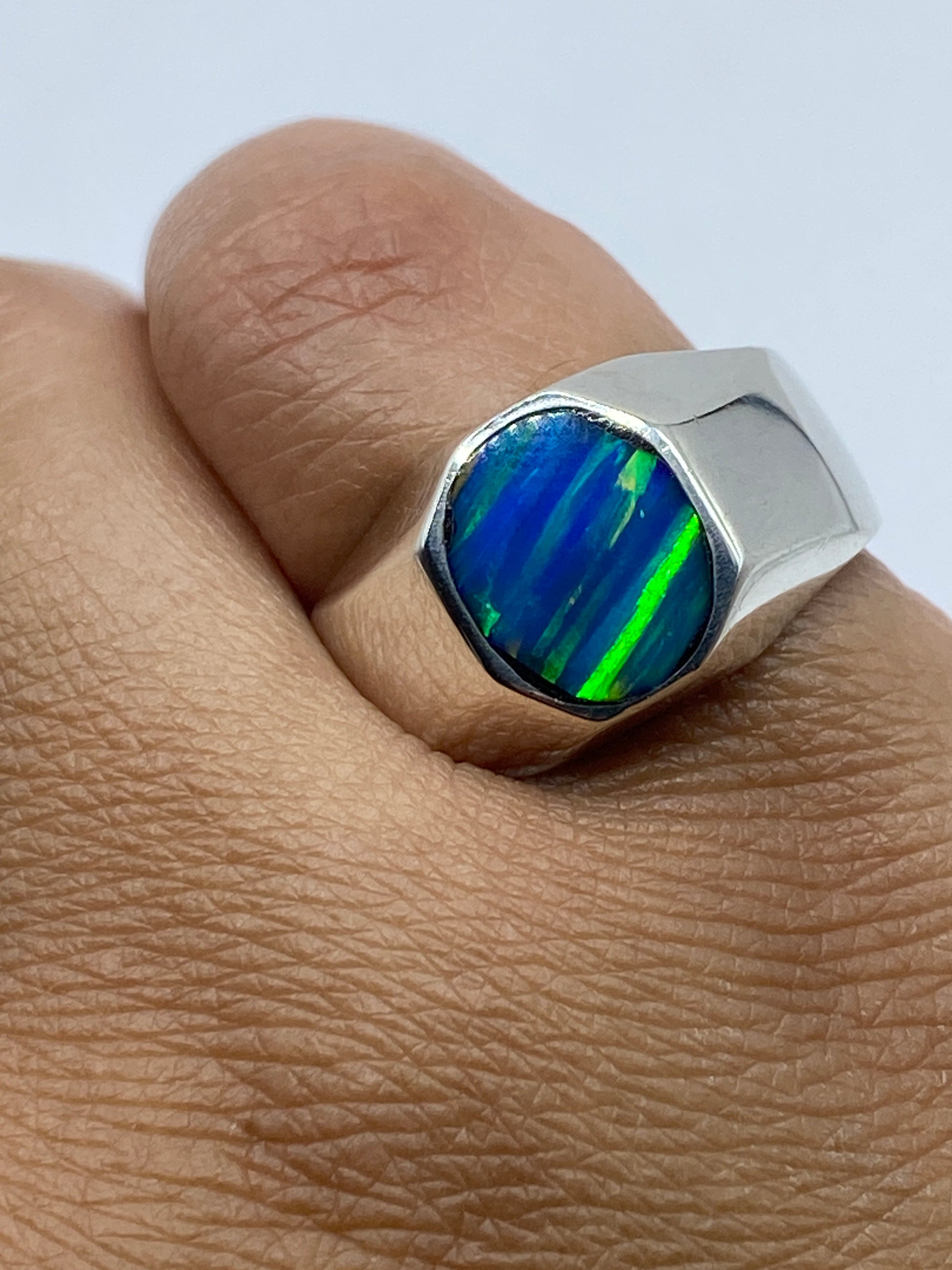 Anillo sello plata con ópalo azul sobre superficie gris mostrando sello .925