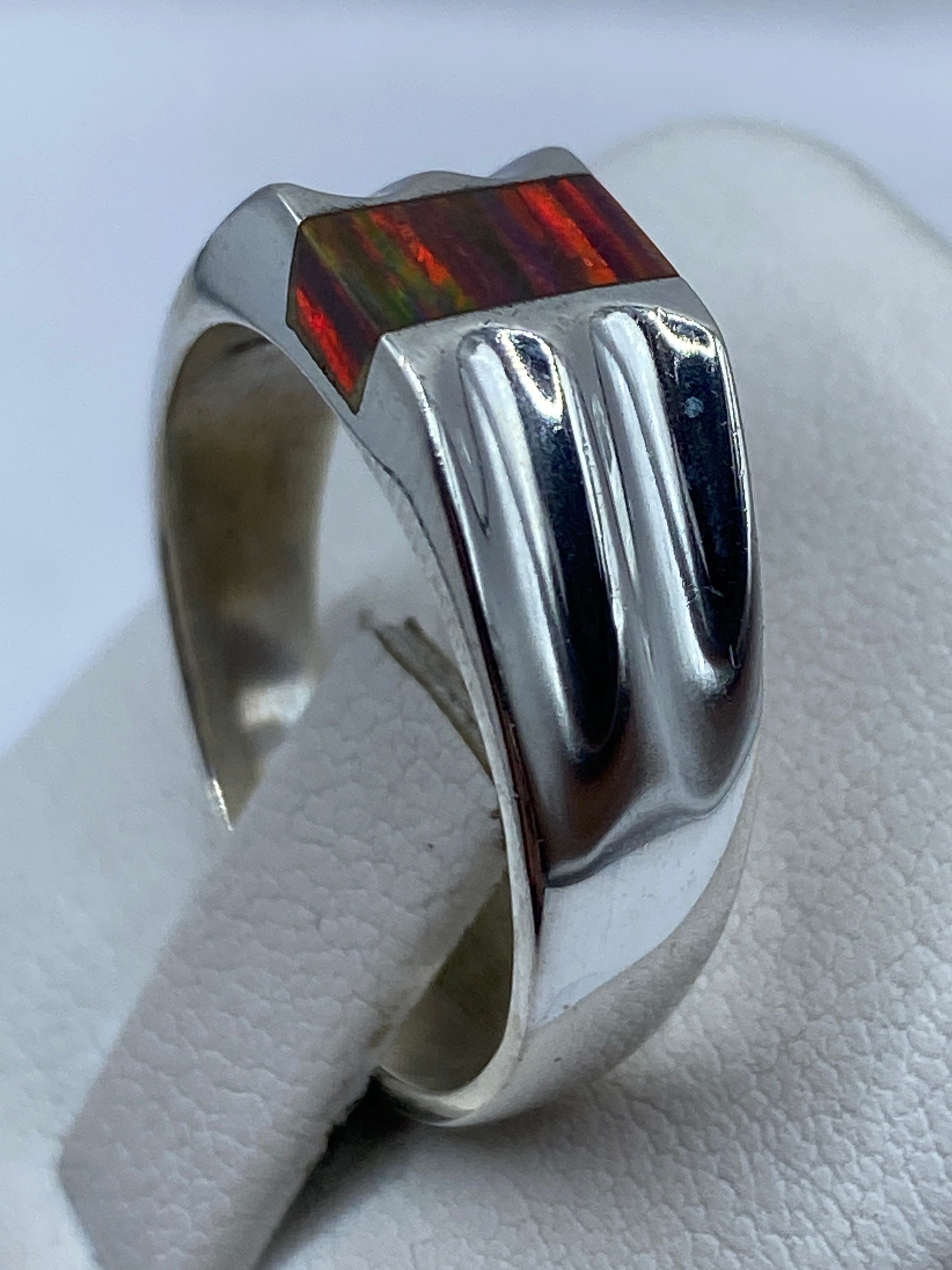 Detalle de los dedos con el anillo de ópalo de fuego brillando con colores naturales