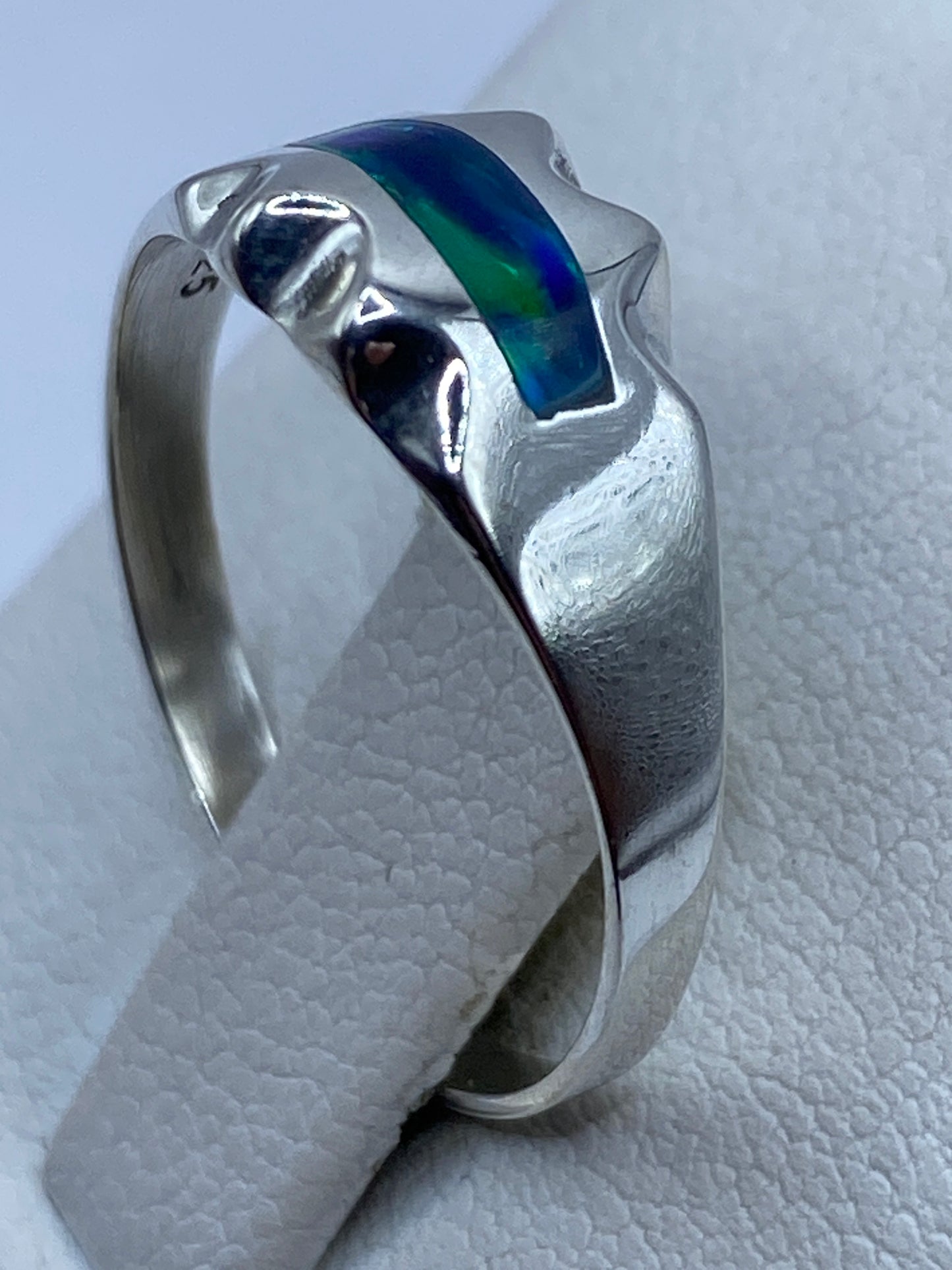 Anillo ópalo de fuego en mano mostrando el diseño ondulado de la banda