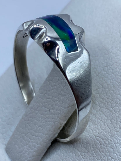 Anillo ópalo de fuego en mano mostrando el diseño ondulado de la banda