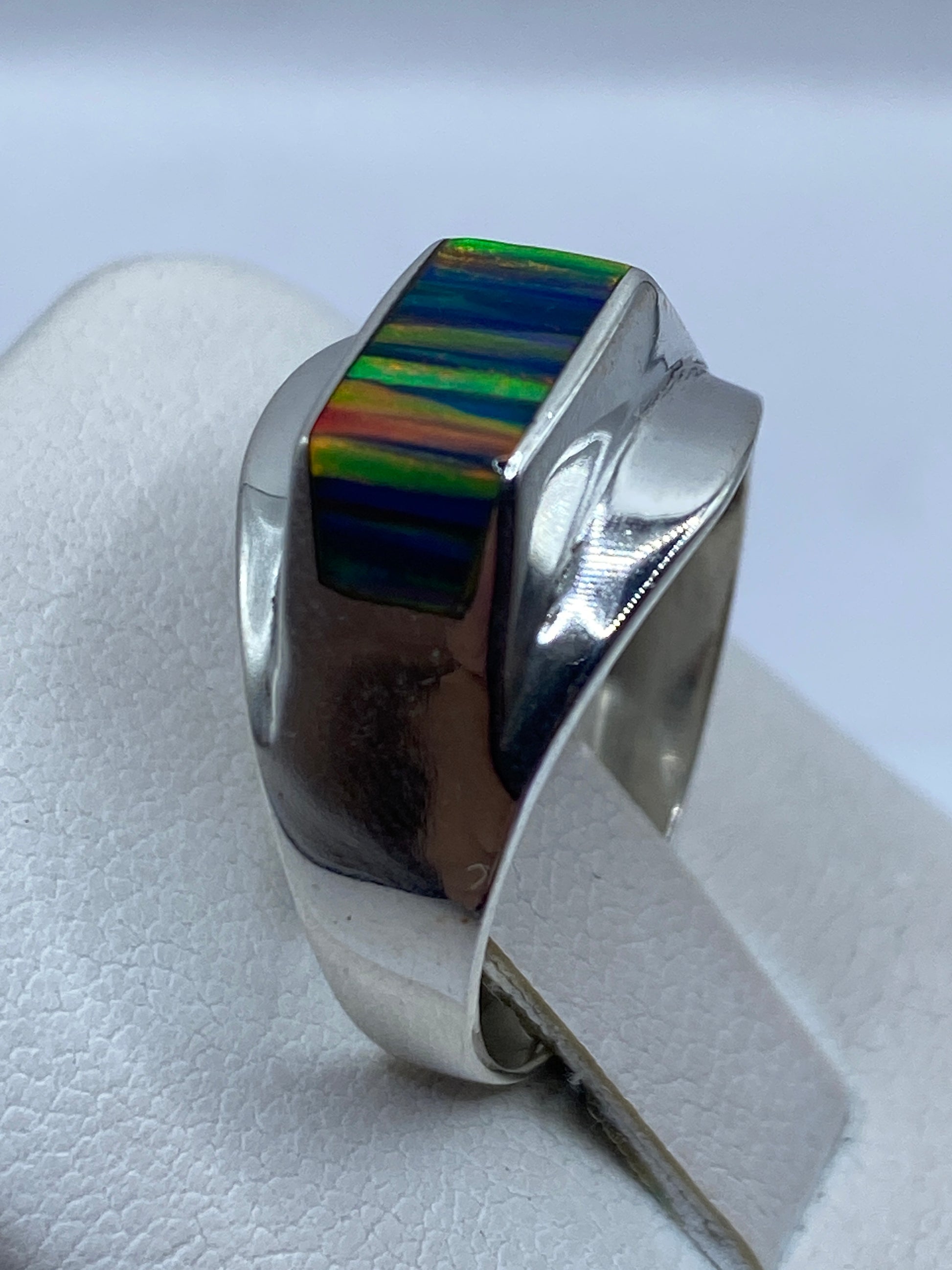 Anillo de plata en dedo mostrando el juego de colores azul del ópalo natural