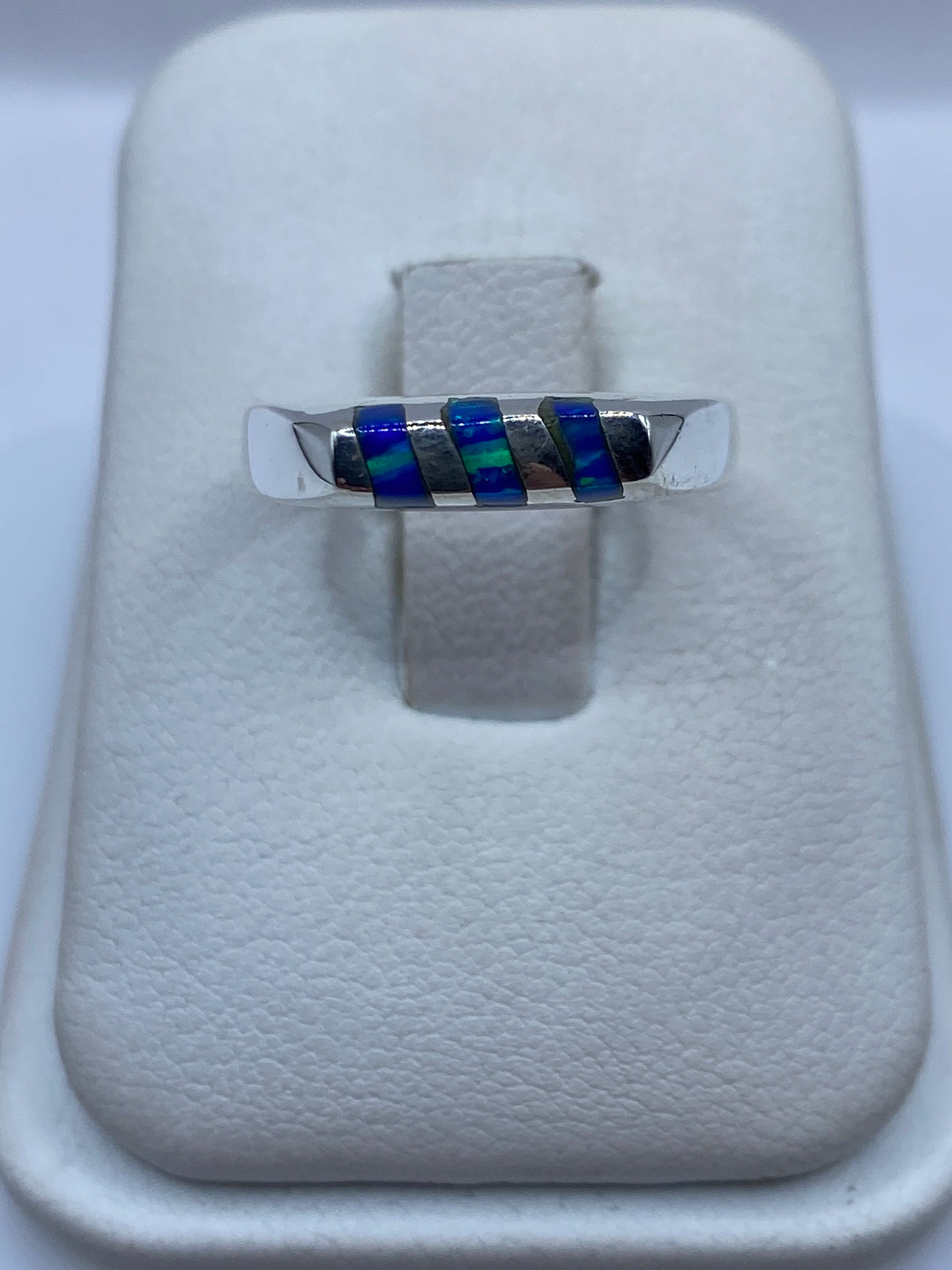 Anillo de plata con ópalo de fuego azul engastado, vista frontal sobre exhibidor blanco