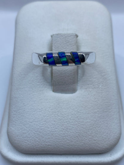 Anillo de plata con ópalo de fuego azul engastado, vista frontal sobre exhibidor blanco