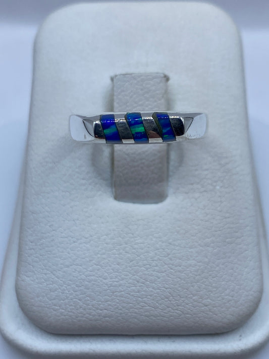 Anillo de plata con ópalo de fuego azul engastado, vista frontal sobre exhibidor blanco