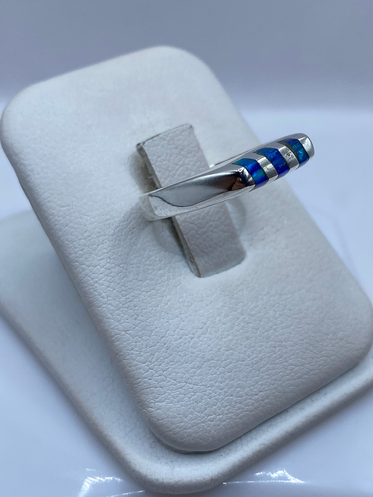 Anillo unisex de plata .925 con ópalo azul en la mano, mostrando el juego de luz