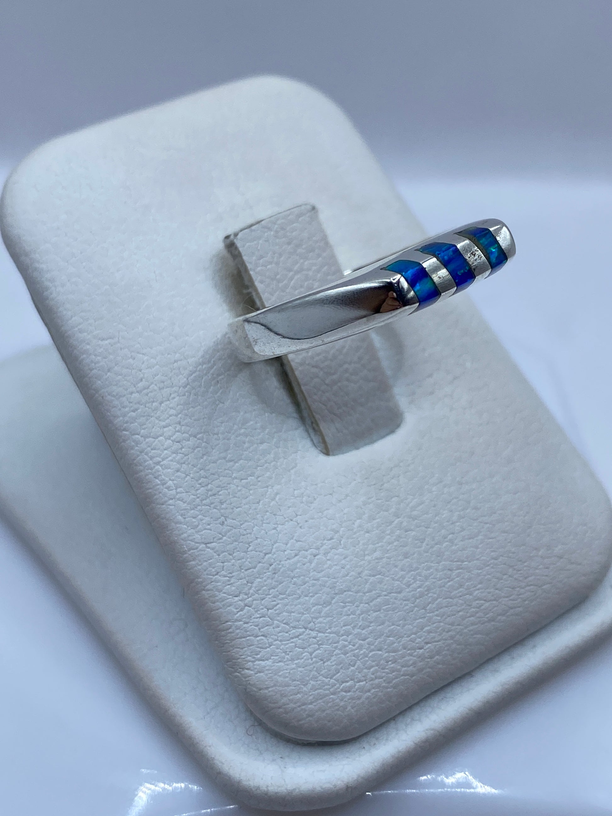 Anillo unisex de plata .925 con ópalo azul en la mano, mostrando el juego de luz