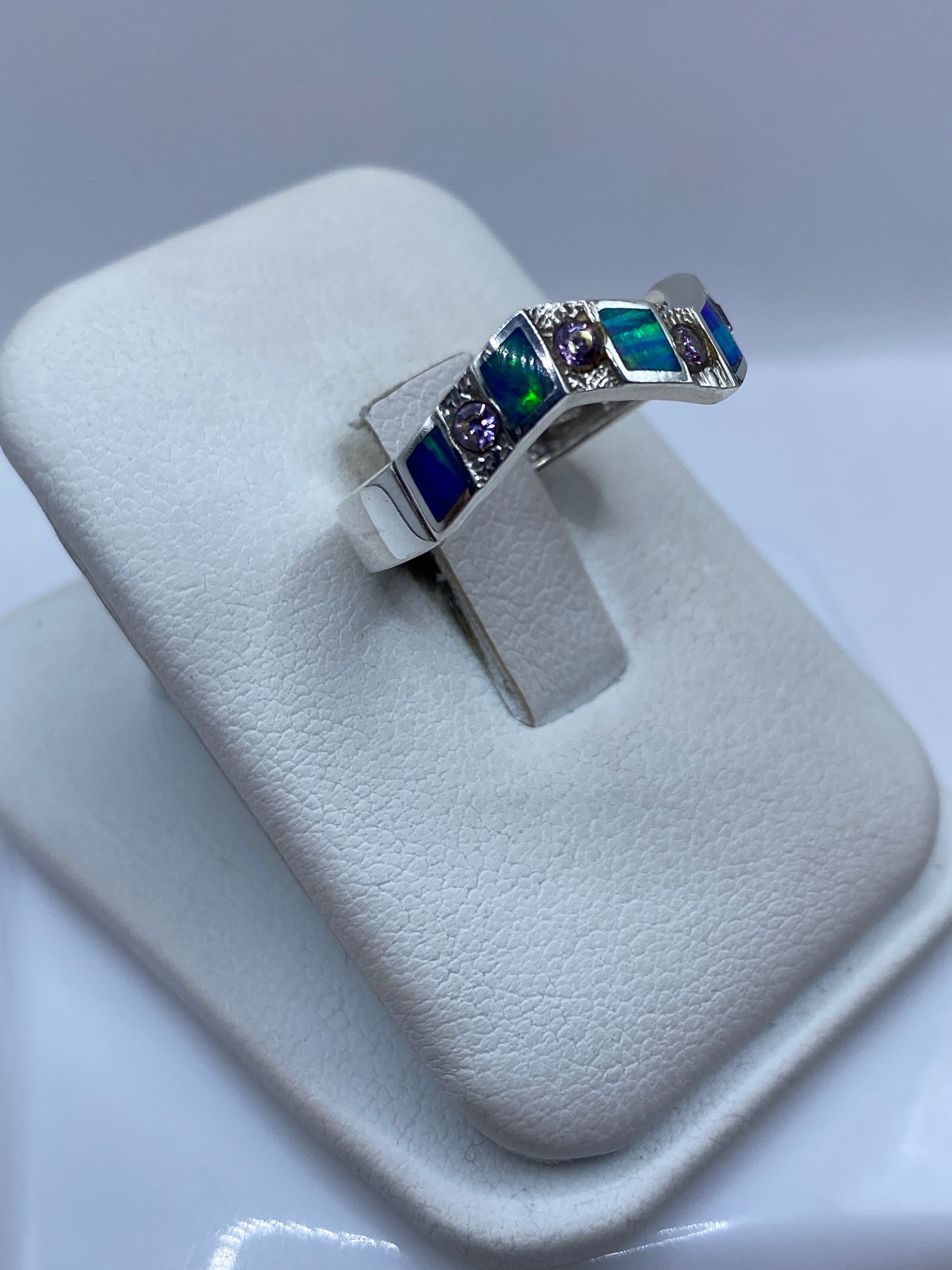Anillo ópalo de fuego azul en la mano de una mujer mostrando el juego de color natural