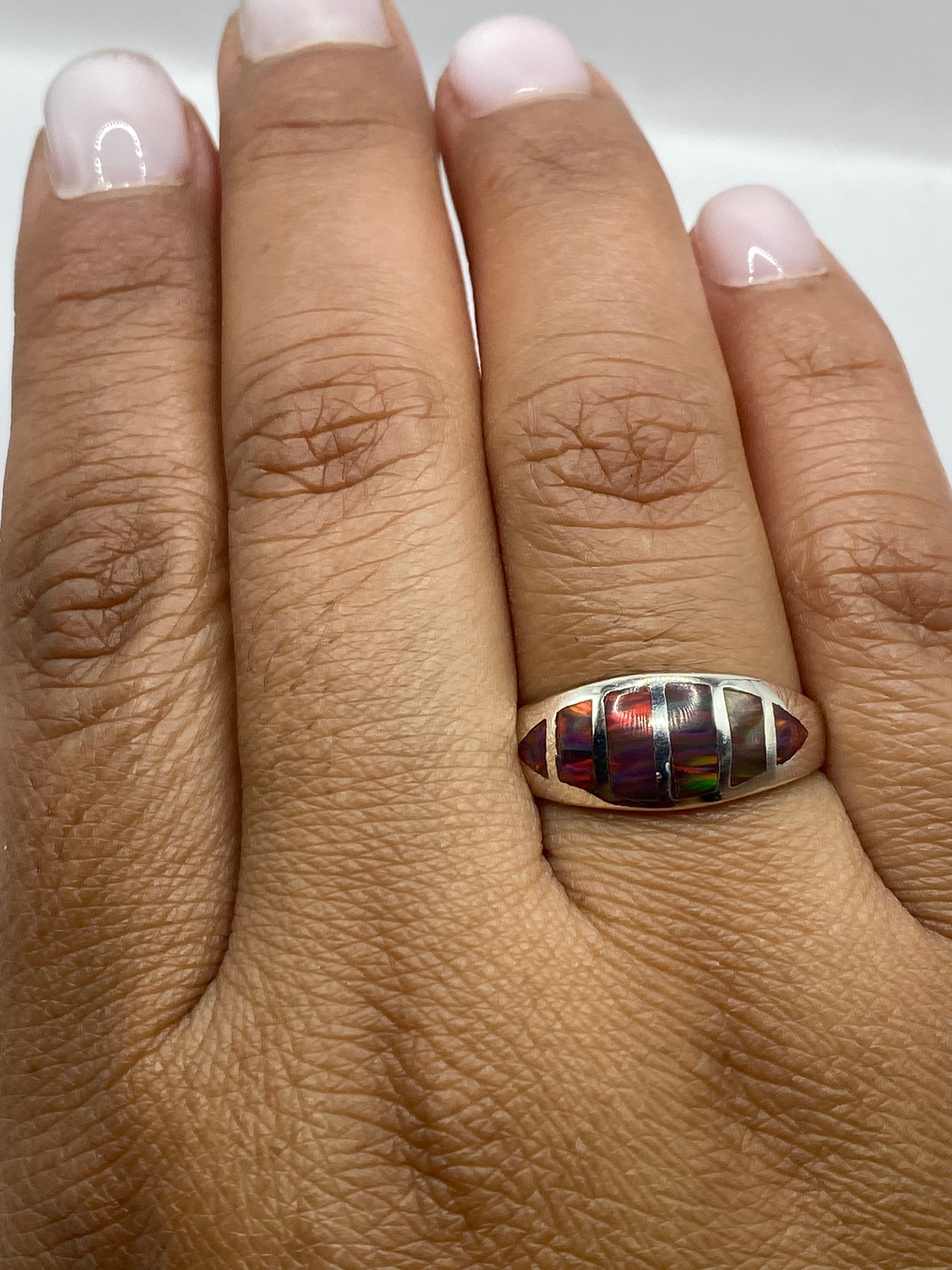 Anillo de ópalo de fuego en la mano de una persona, mostrando la intensidad de los colores naturales