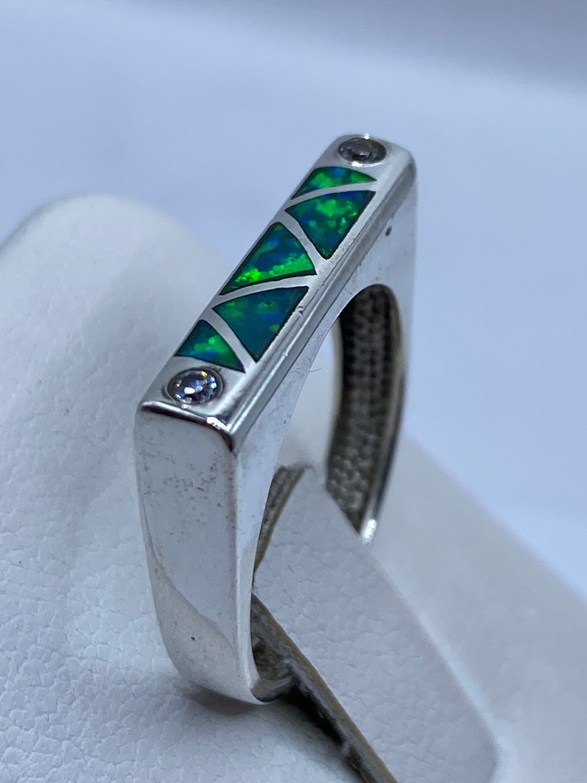 Anillo puesto en mano de mujer, ópalo verde limón brillando con luz natural
