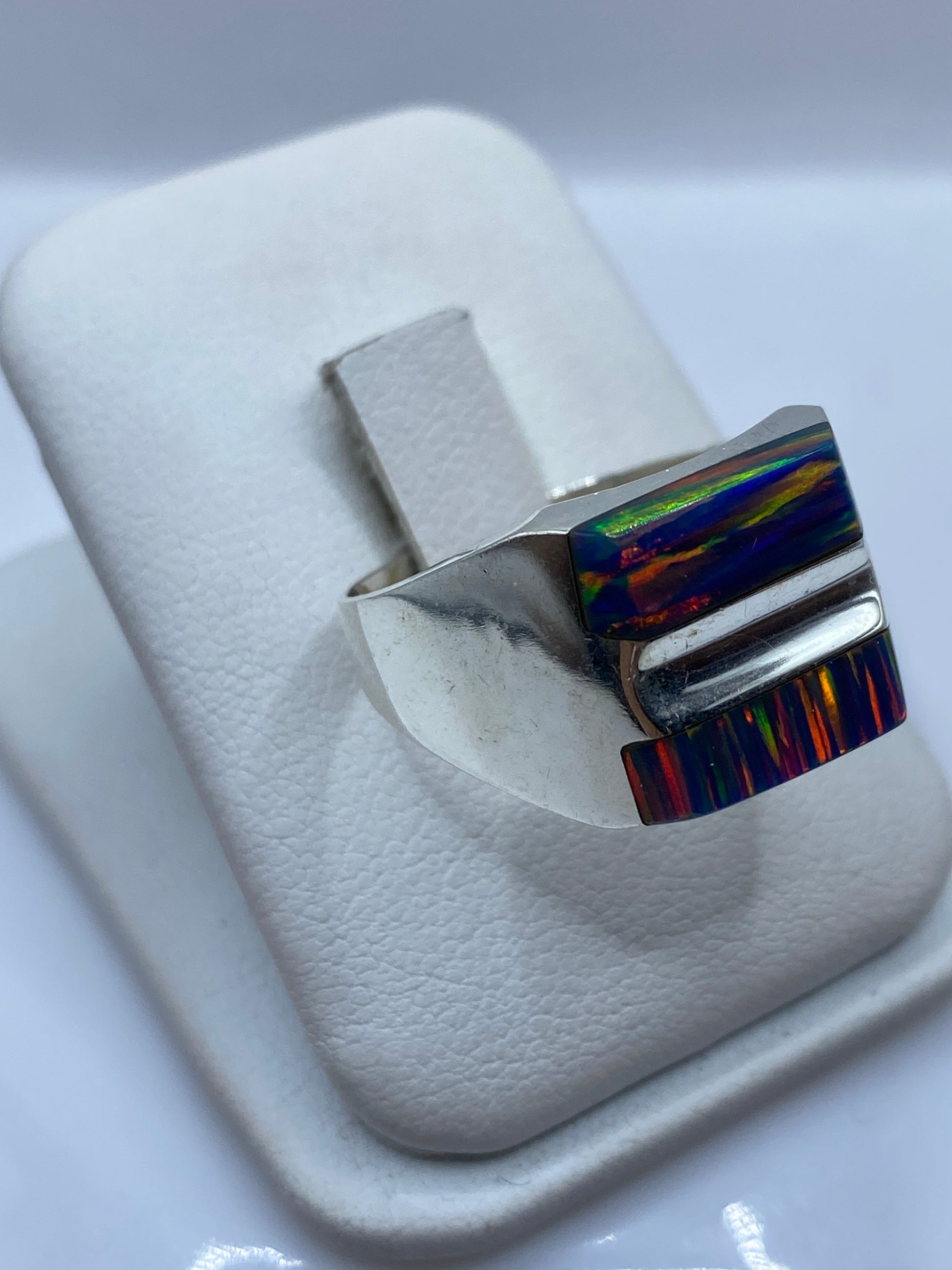 Detalle frontal del anillo mostrando el ópalo de fuego con fuego rojo, naranja y verde
