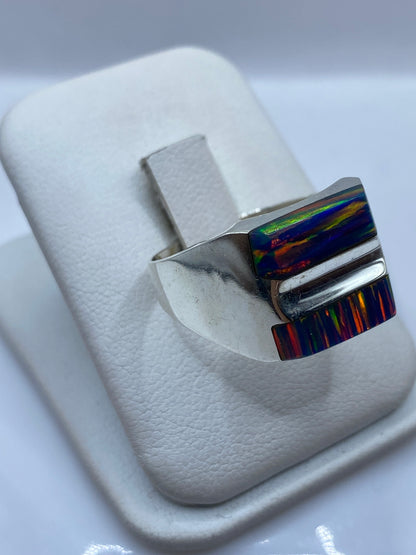 Detalle frontal del anillo mostrando el ópalo de fuego con fuego rojo, naranja y verde