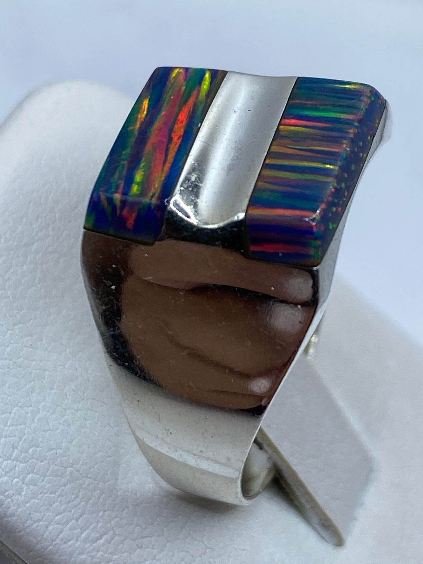 Anillo ópalo de fuego en la mano mostrando el juego de colores bajo luz natural