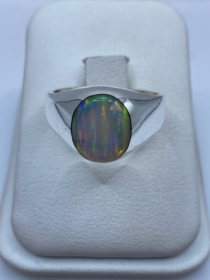 Anillo de plata solitario con ópalo de fuego multicolor mostrando juego de colores naranjas, verdes y azules
