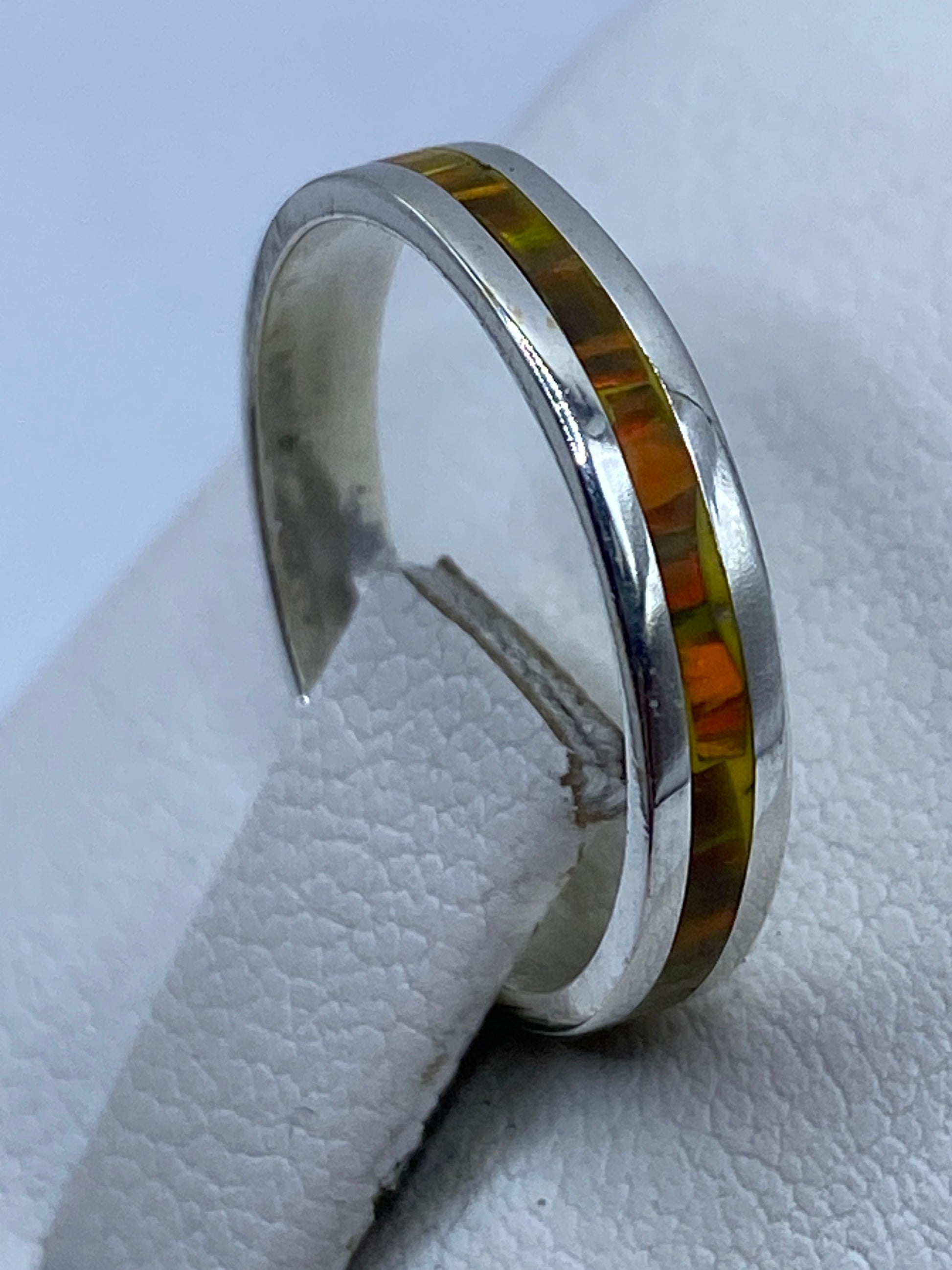 Anillo solitario minimalista en la mano, luciendo el fuego amarillo del ópalo