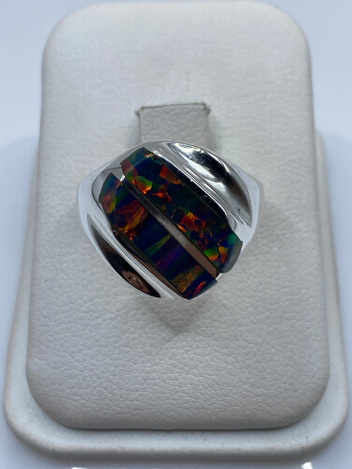 Anillo de plata .925 con ópalo de fuego multicolor mostrando juego de colores azul, naranja y verde en la mano