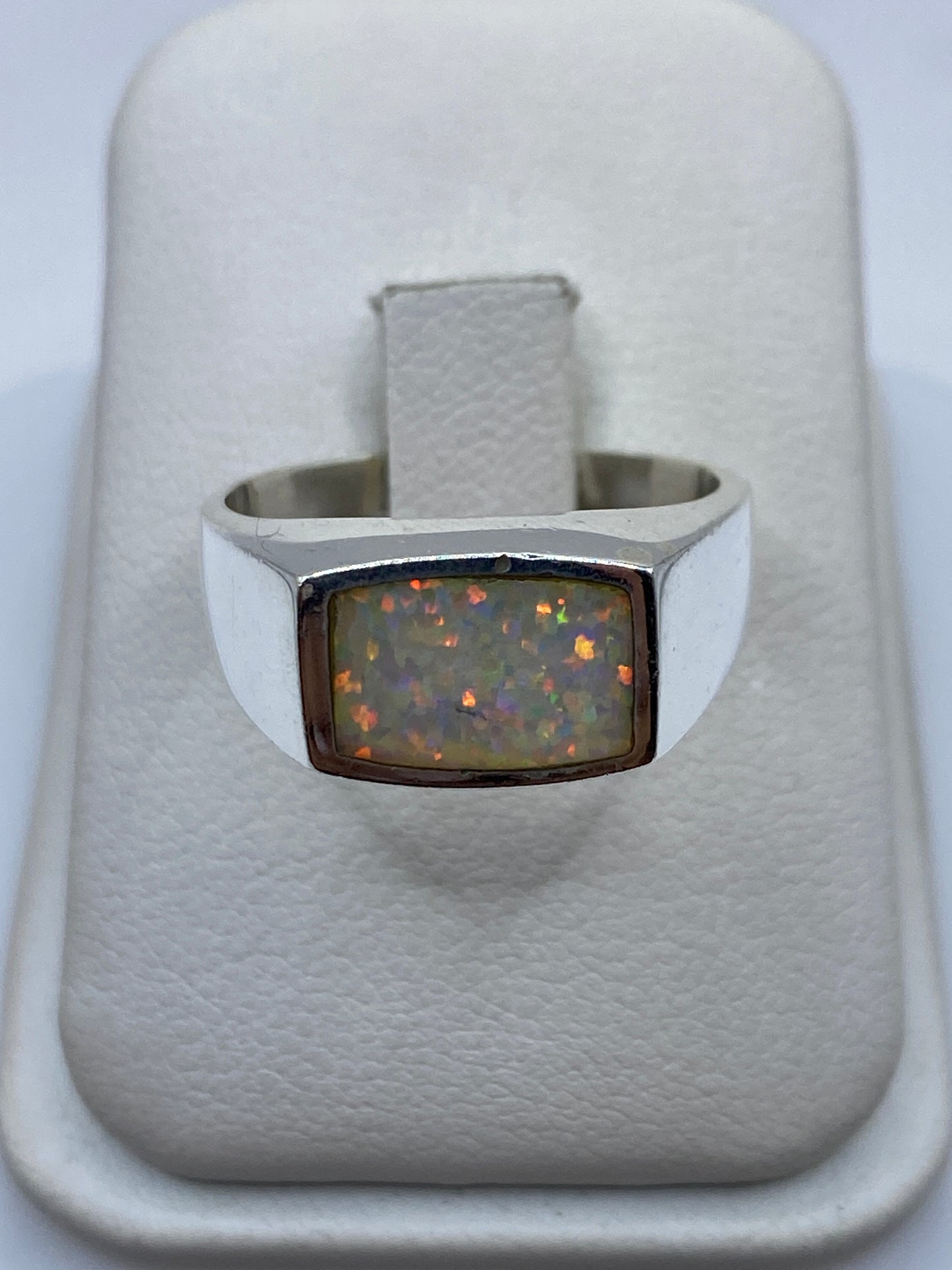 Anillo de plata .950 con ópalo de fuego multicolor en caja blanca, vista superior mostrando el juego de colores