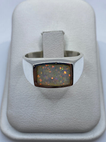 Anillo de plata .950 con ópalo de fuego multicolor en caja blanca, vista superior mostrando el juego de colores