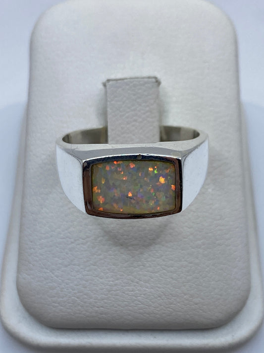 Anillo de plata .950 con ópalo de fuego multicolor en caja blanca, vista superior mostrando el juego de colores