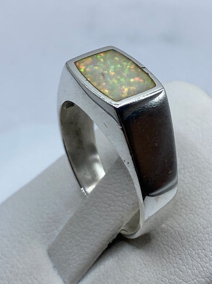Anillo con ópalo fuego natural en la mano, demostrando el cambio de colores con la luz