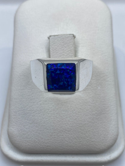 Anillo solitario de plata 950 con ópalo de fuego azul natural, visto desde arriba en la mano