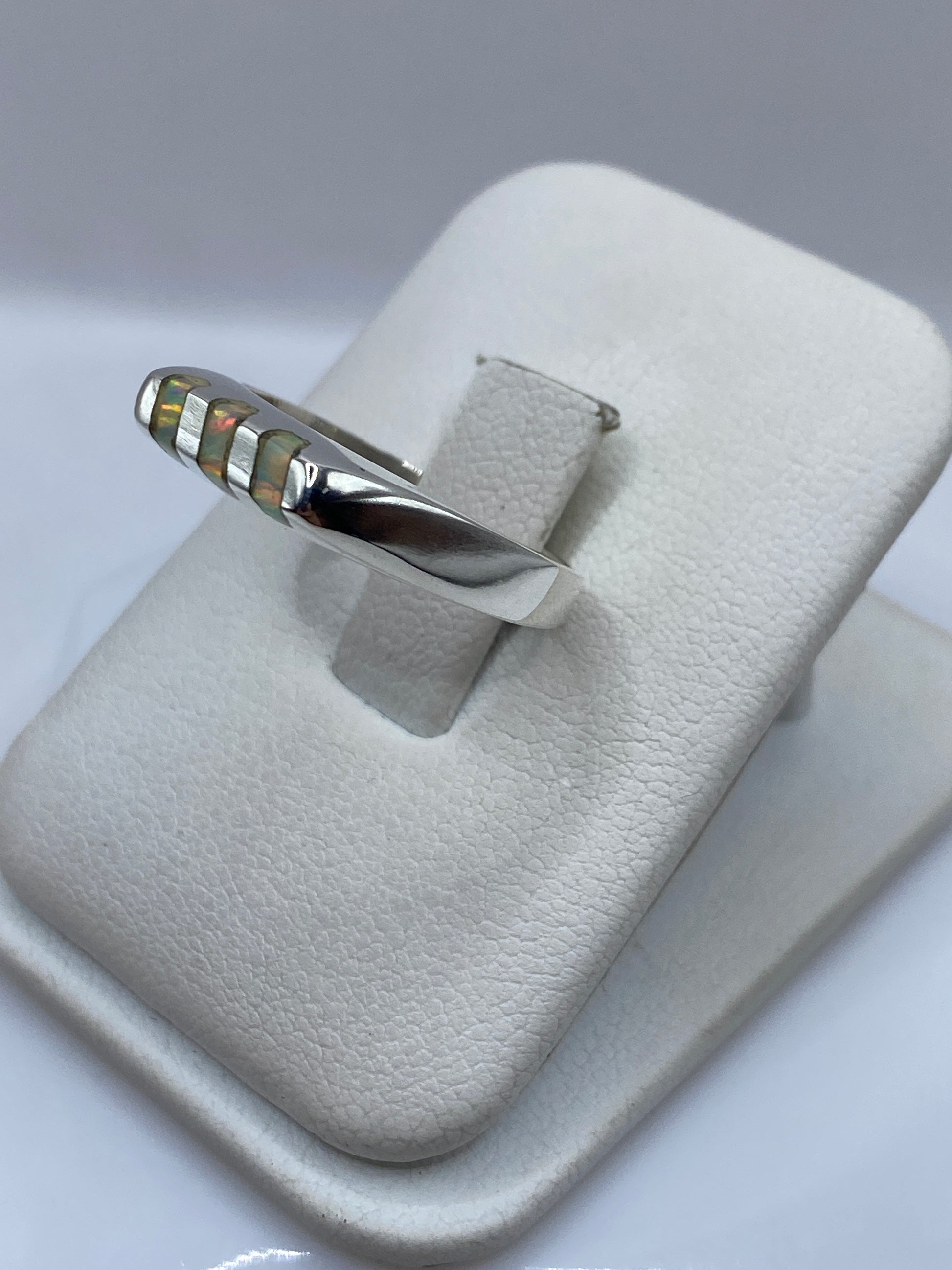 Vista lateral de anillo unisex de banda en plata con ópalo de fuego engastado