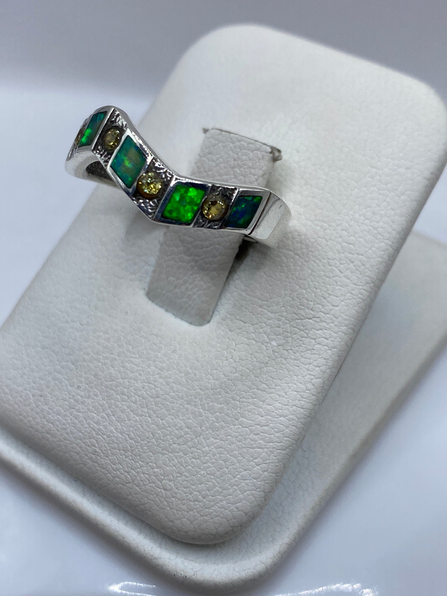 Anillo geométrico con ópalo natural mostrando juego de color verde y azul en la mano