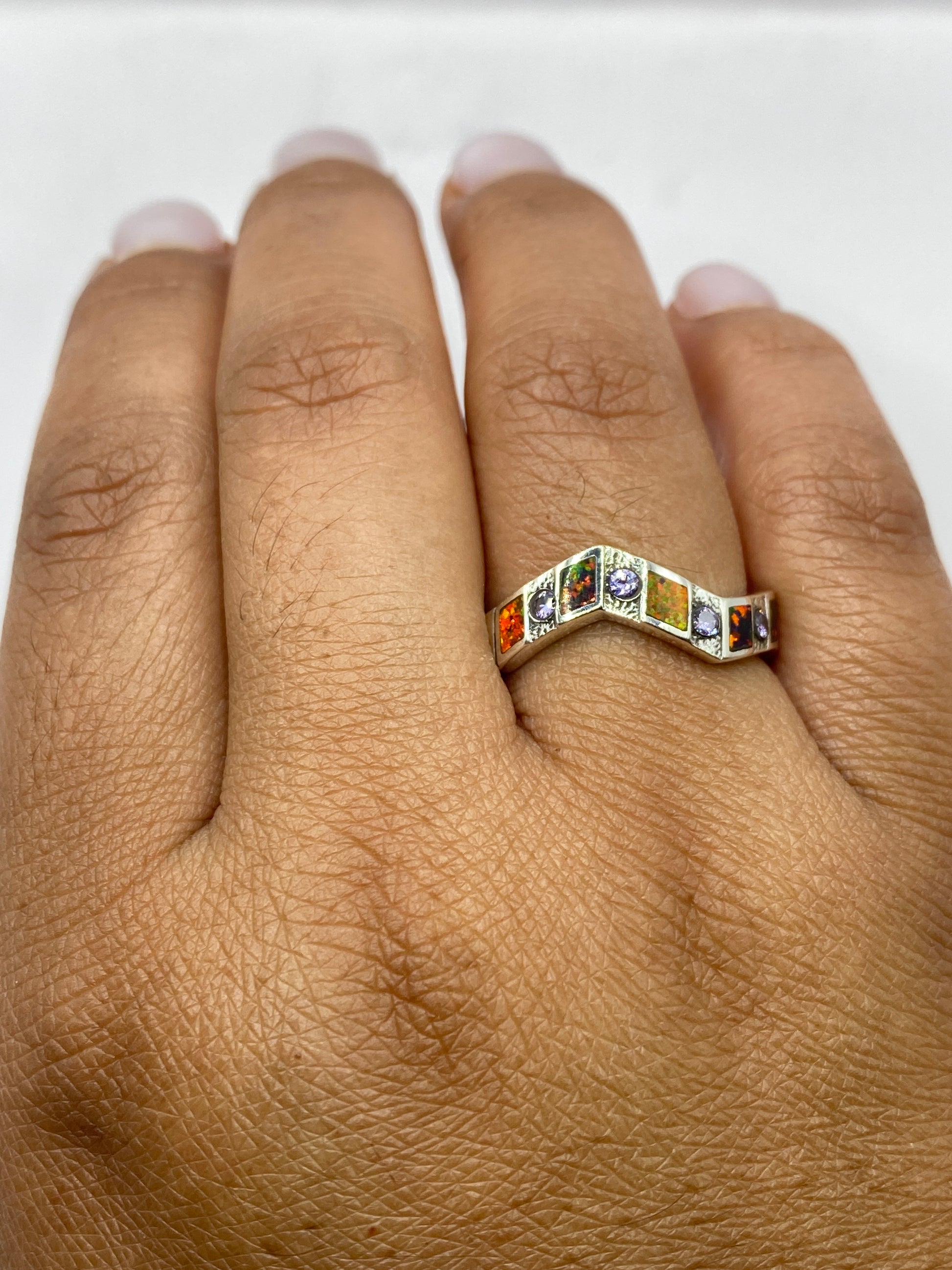 Anillo con piedra ópalo sobre fondo blanco mostrando detalle de la banda texturada