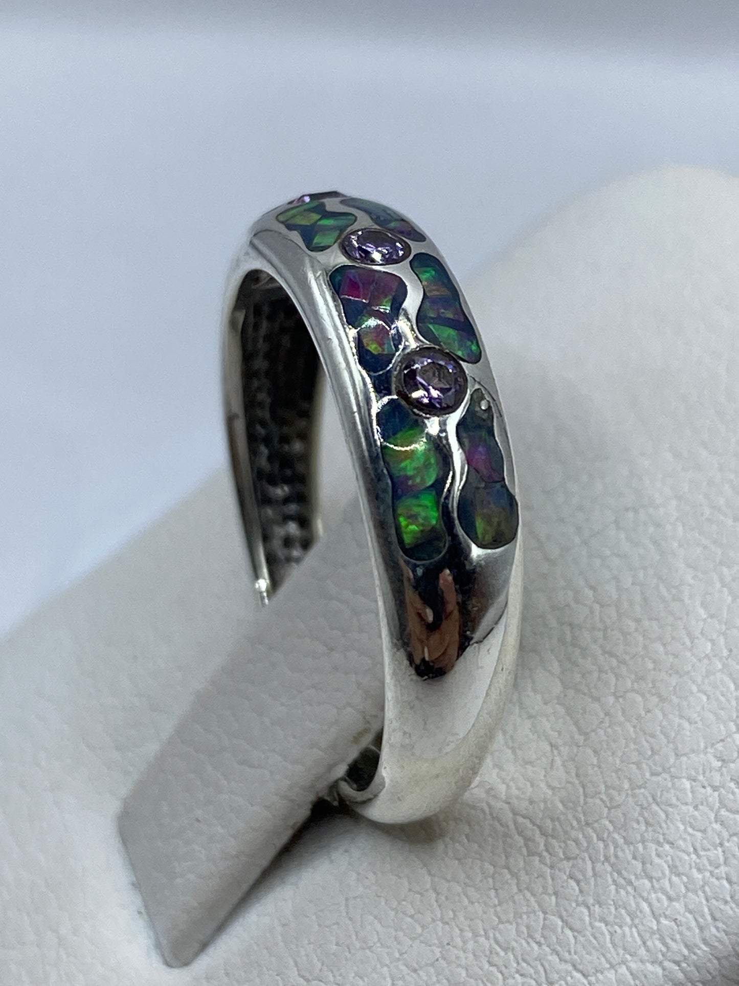 Anillo en la mano mostrando el juego de colores del ópalo natural bajo la luz