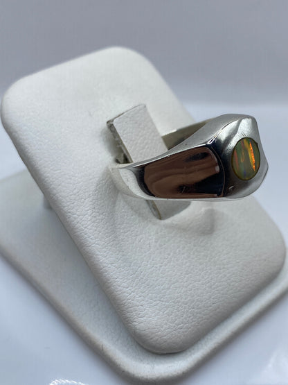 Anillo escultural de plata con ópalo de fuego mostrando juego de rojo y verde desde el lateral