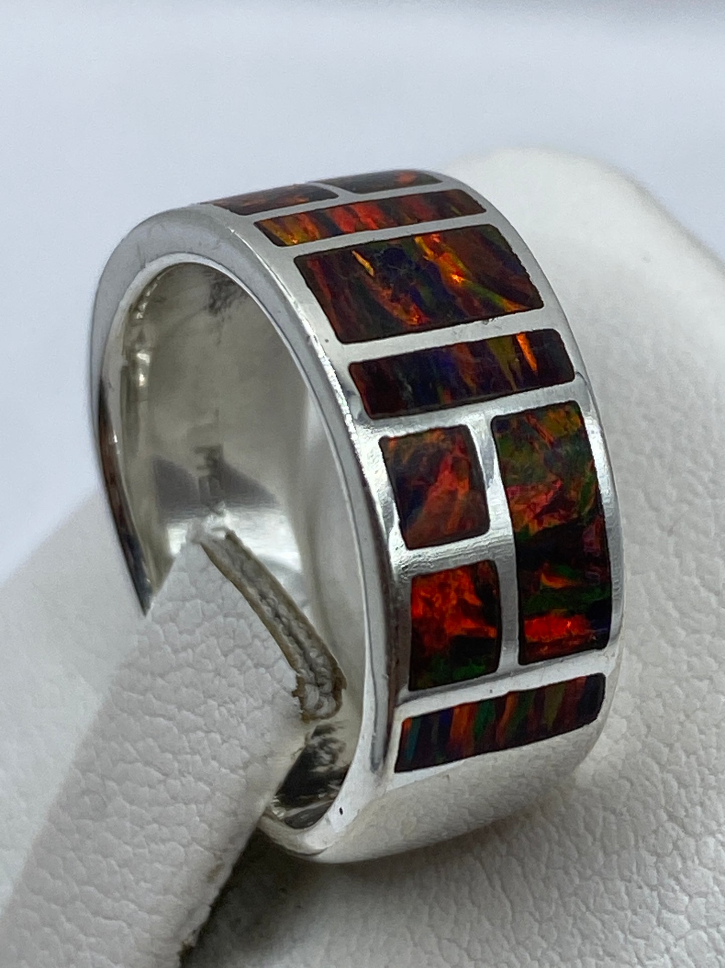 Anillo de ópalo visto desde el costado en dedo con sello 950 visible en la banda