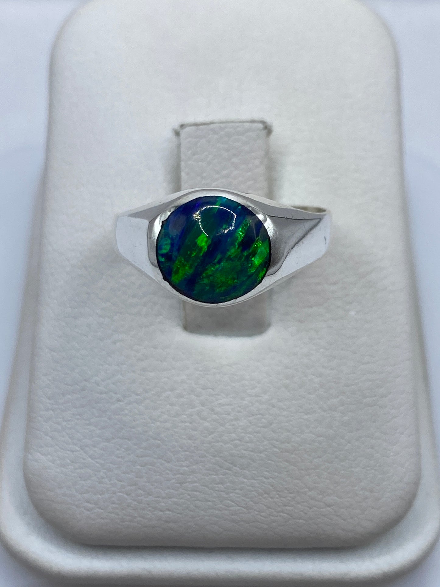 Anillo de plata .925 con ópalo de fuego azul sobre dedo, mostrando el juego de luz cromático