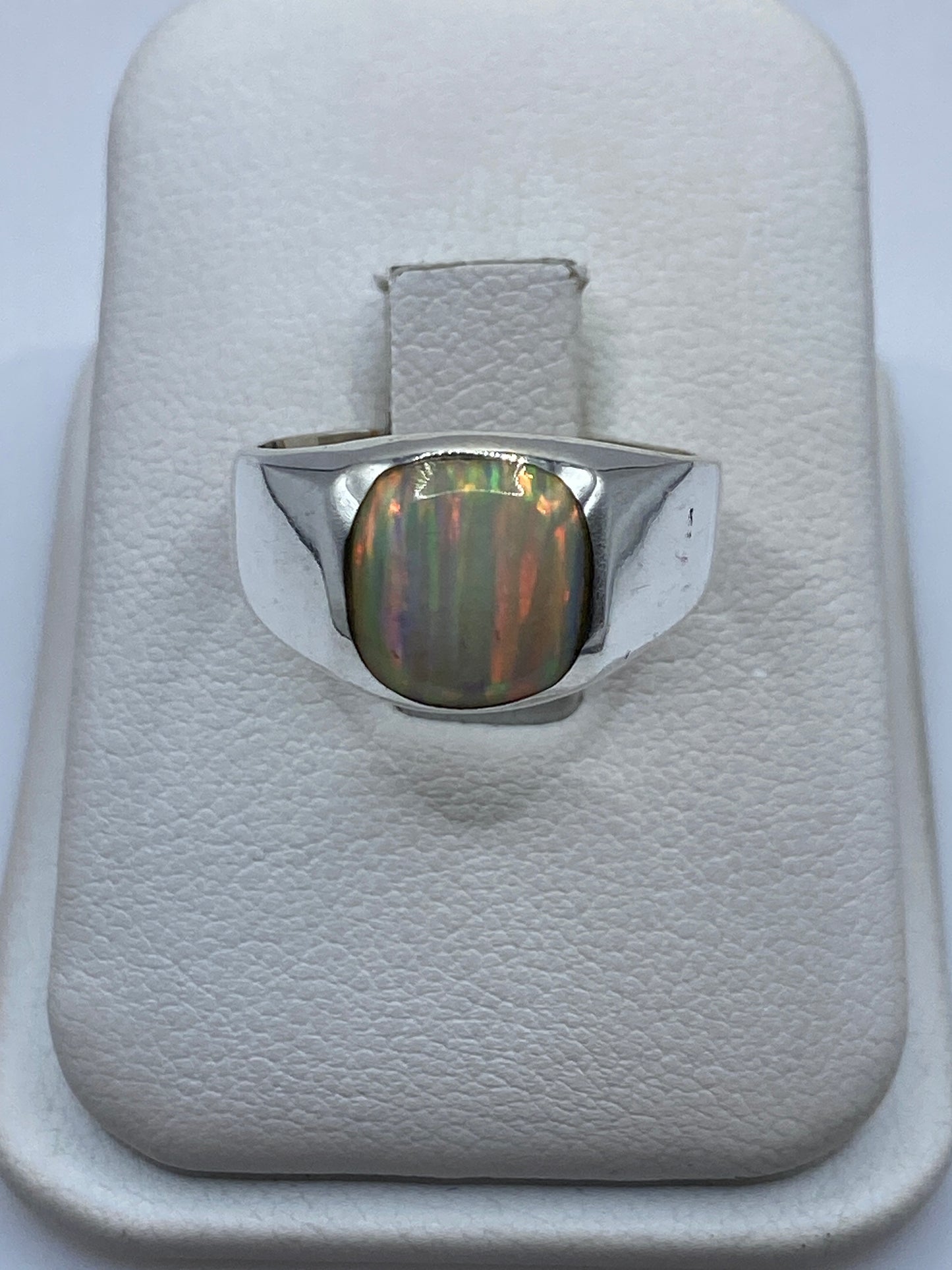 Anillo de plata .950 con ópalo de fuego natural en estuche blanco mostrando el juego de colores iridiscente