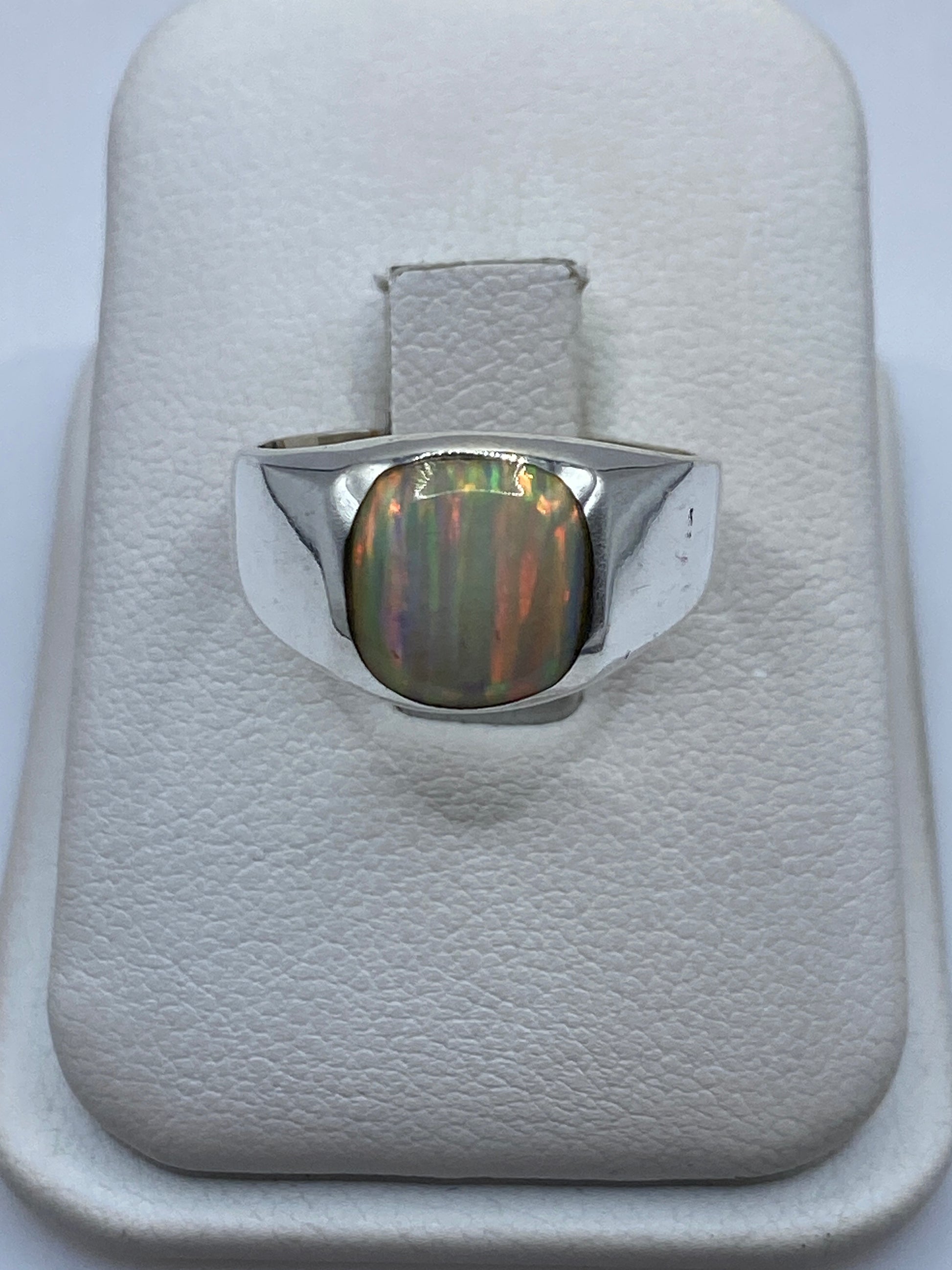 Anillo de plata .950 con ópalo de fuego natural en estuche blanco mostrando el juego de colores iridiscente