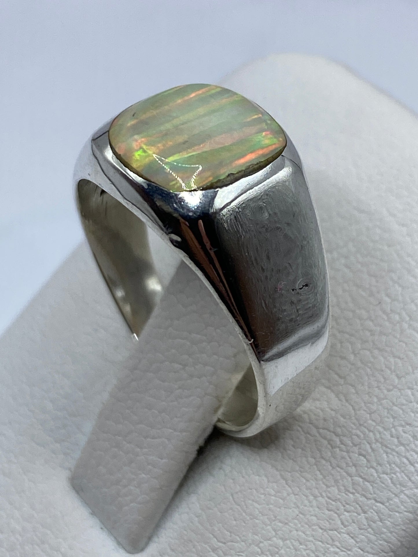 Anillo de plata .950 puesto en la mano, diseño arquitectónico con ópalo de fuego brillando