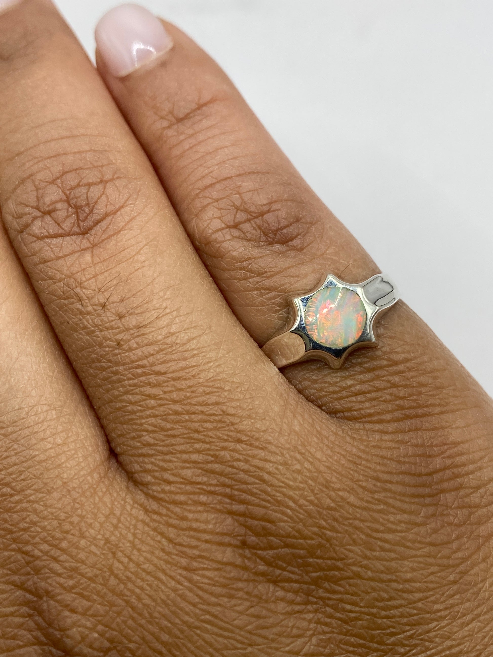 Anillo ópalo de fuego en mano mostrando brillo y movimiento de la piedra natural