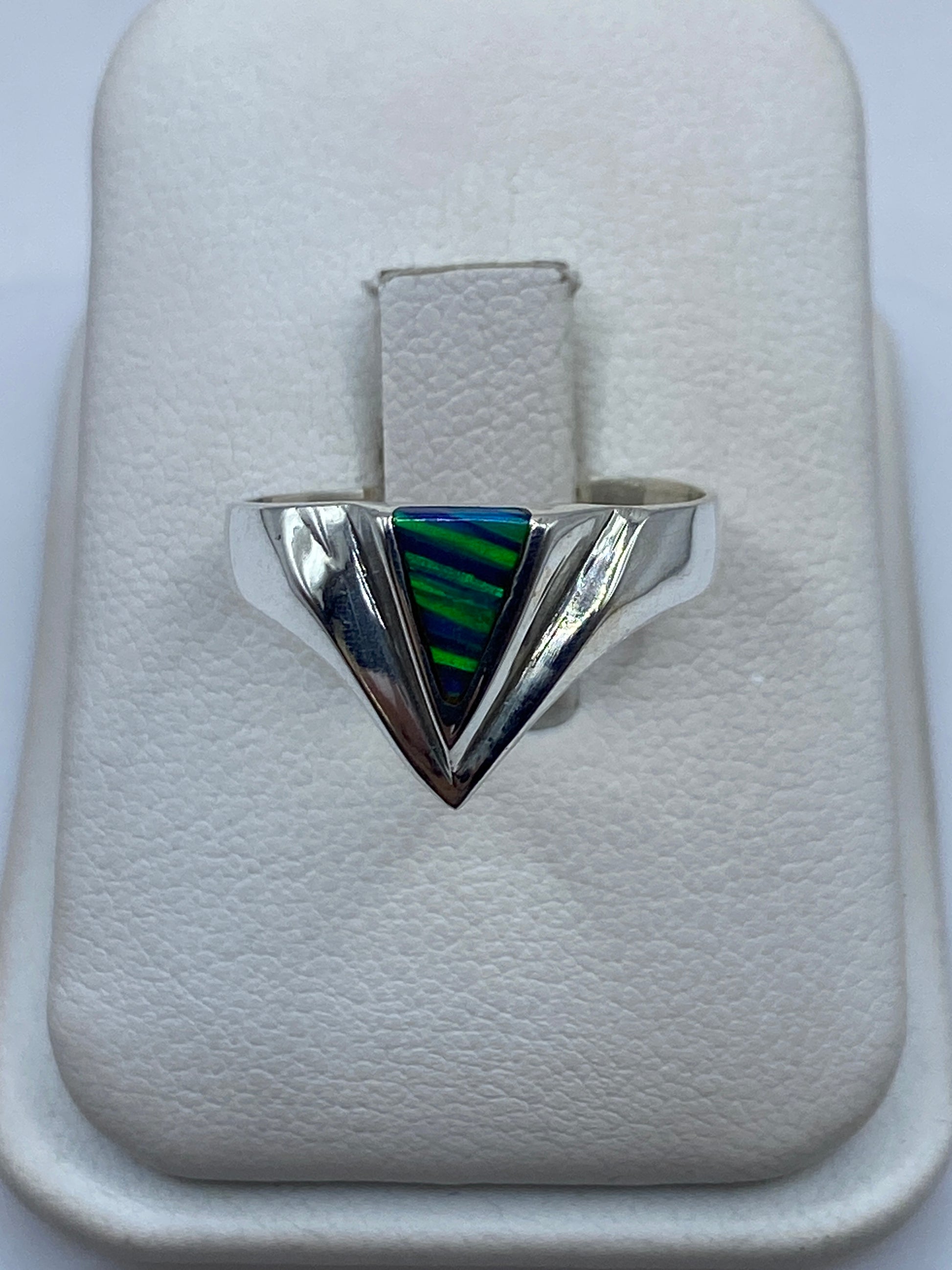 Anillo de plata triangular con piedra multicolor azul y verde en mano de mujer
