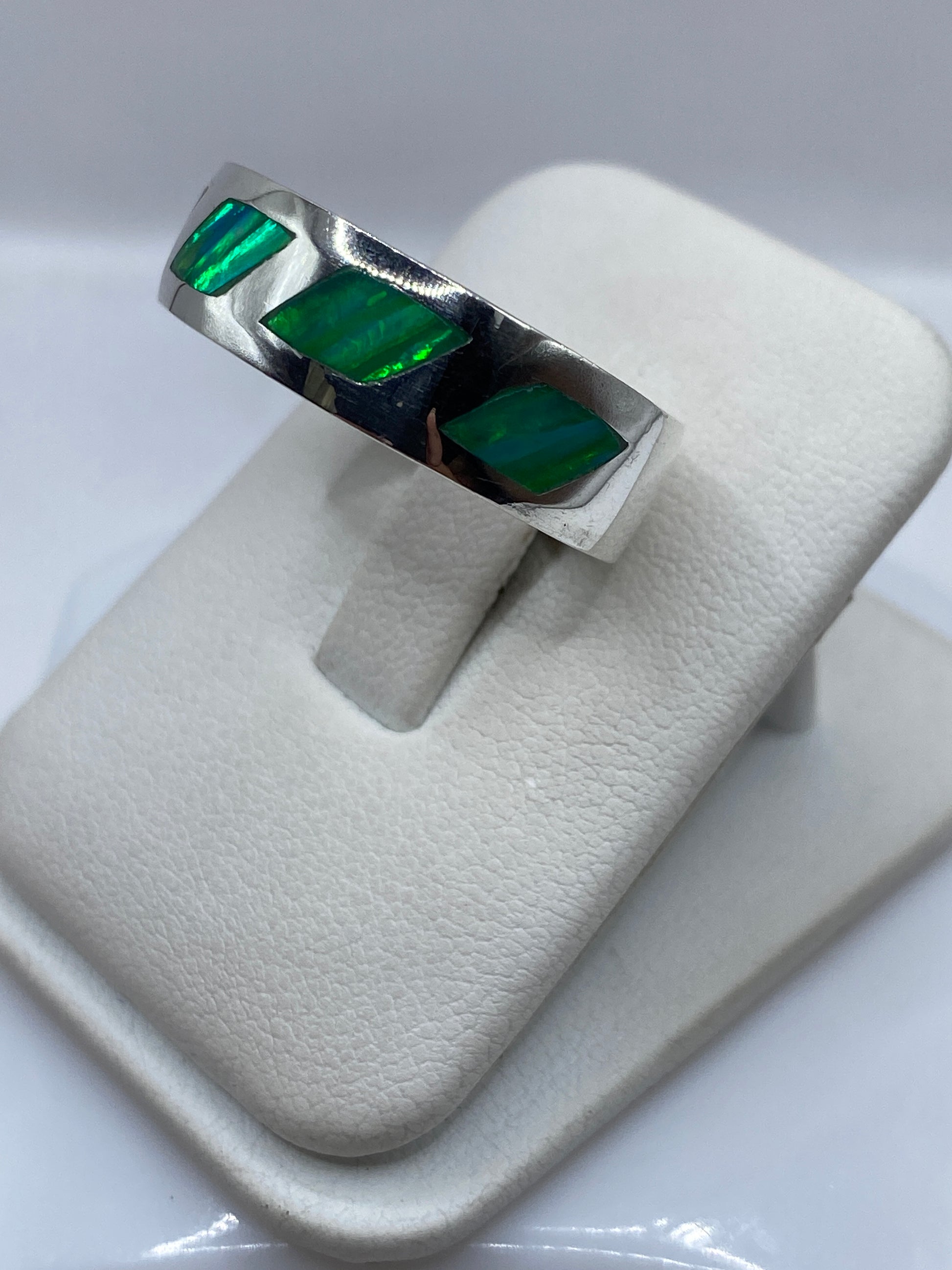 Vista lateral del anillo moderno de plata con piedra ópalo de fuego en tonos verdes