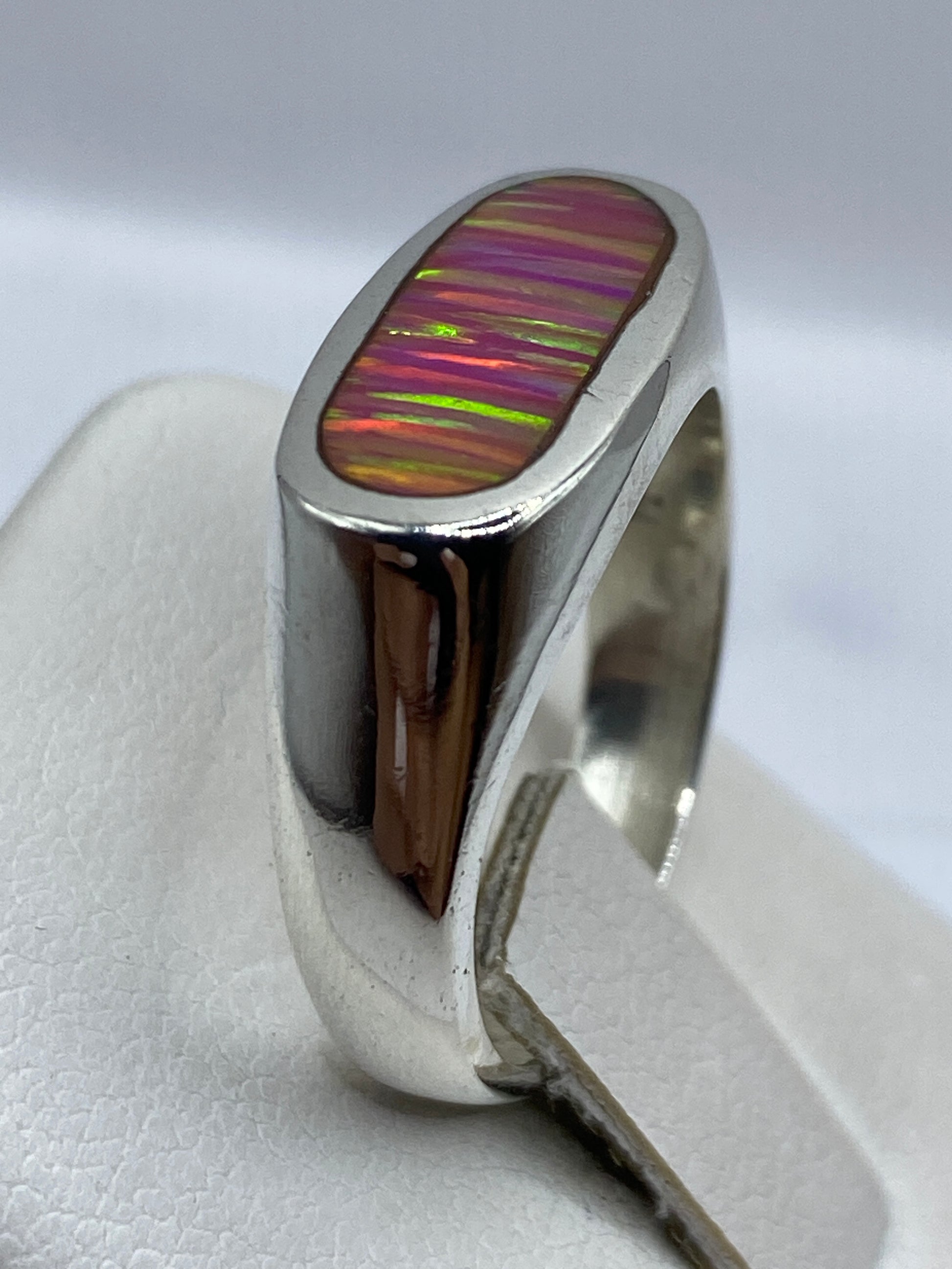 Detalle del ópalo de fuego con juego de colores rosa y coral en la mano