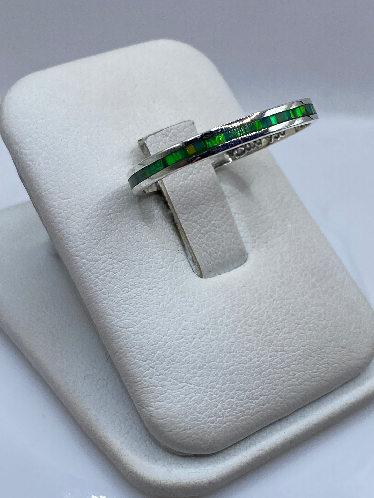 Anillo minimalista unisex en plata pura mostrando el brillo verde del ópalo de fuego