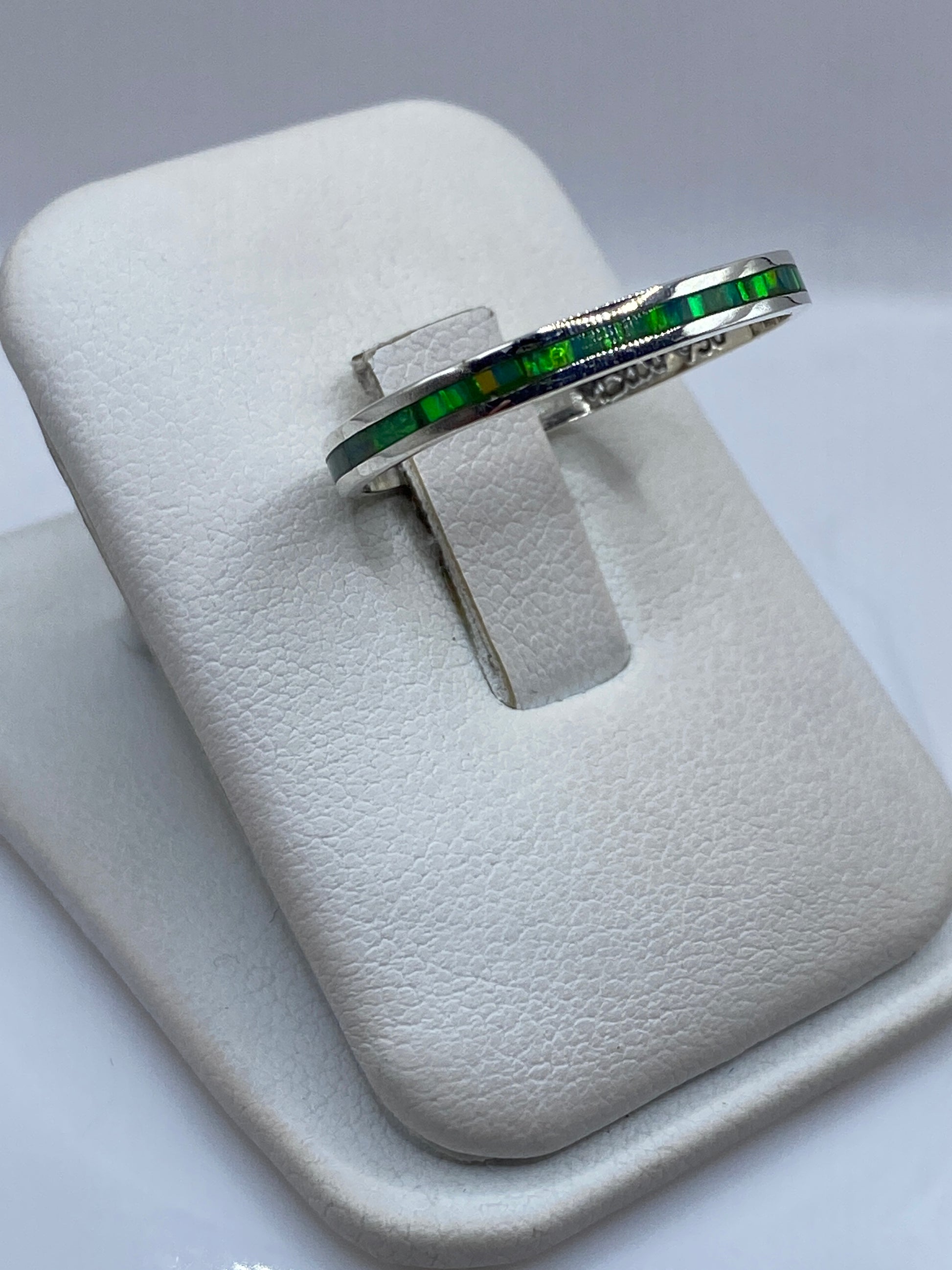 Anillo minimalista unisex en plata pura mostrando el brillo verde del ópalo de fuego
