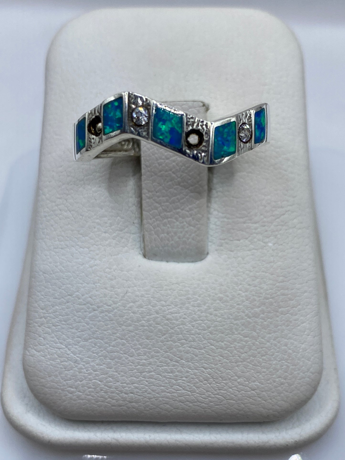Anillo de plata con ópalo de fuego azul geométrico, visto de frente sobre fondo blanco