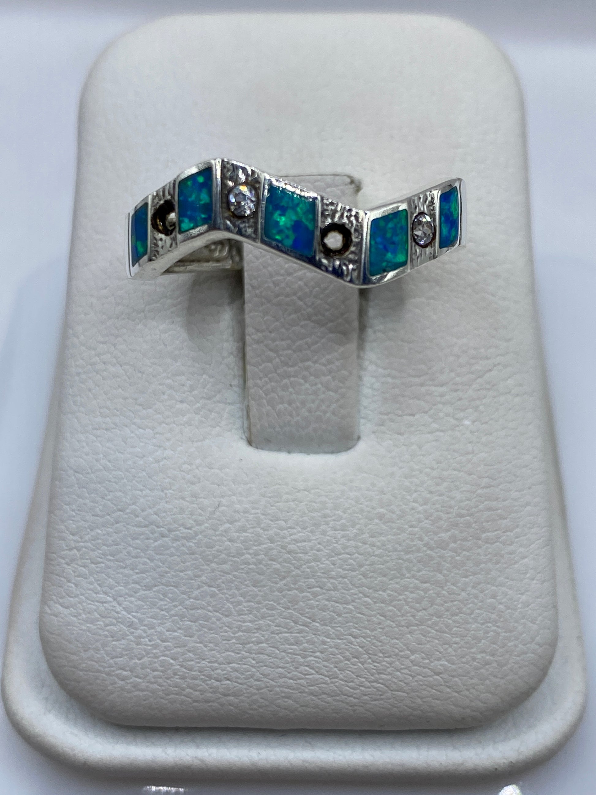 Anillo de plata con ópalo de fuego azul geométrico, visto de frente sobre fondo blanco